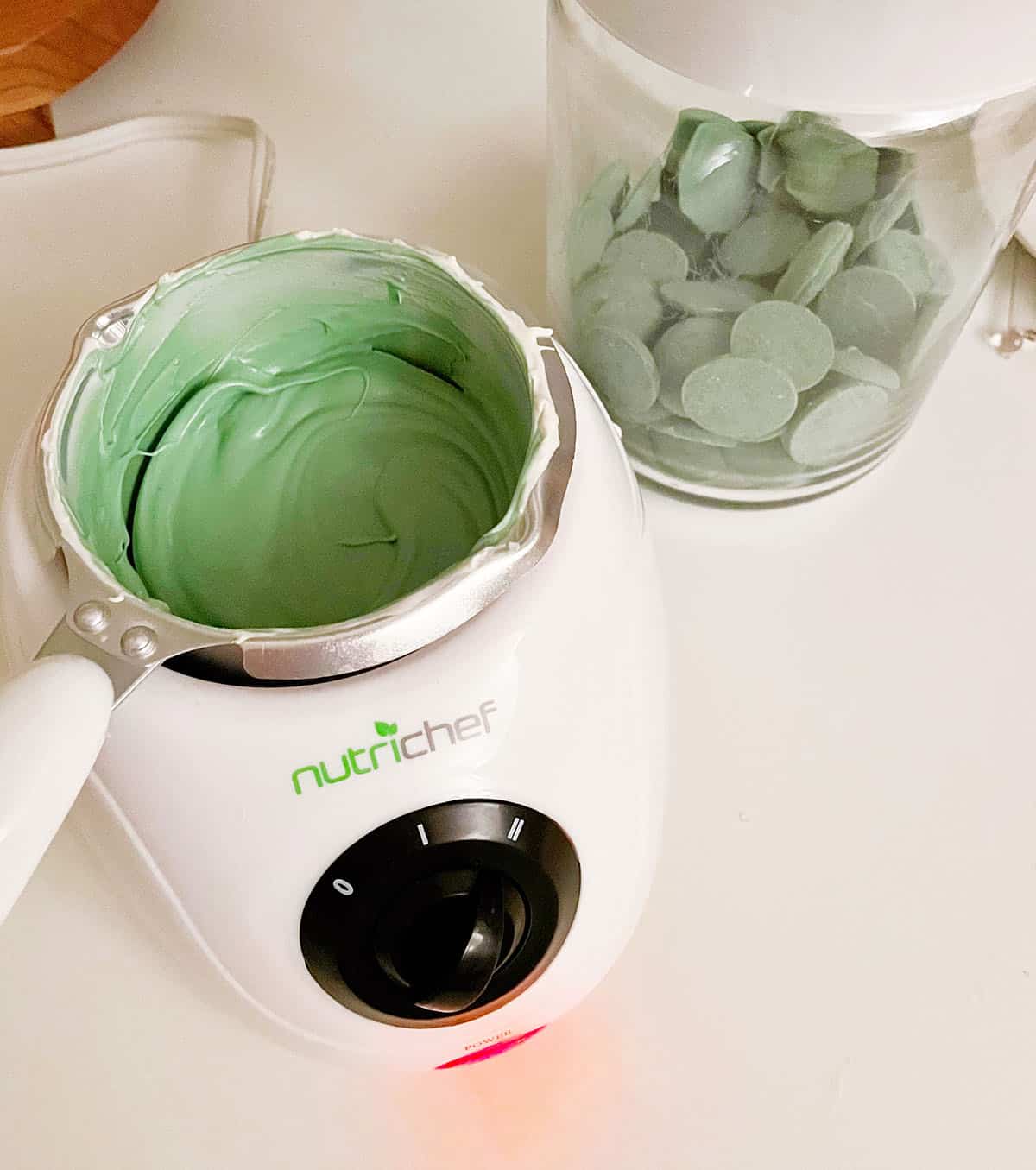 a jar of green candy melts and a measuring cup of melted green candy melts