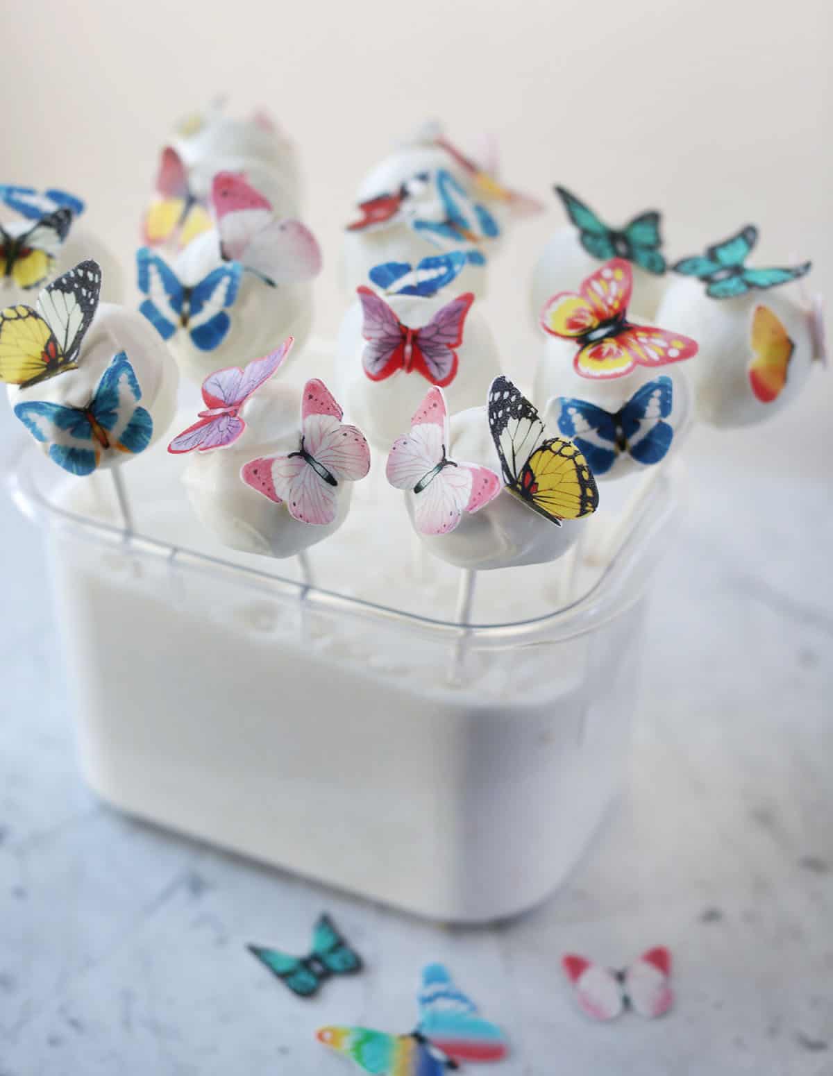 white cake pops with fake butterflies on top