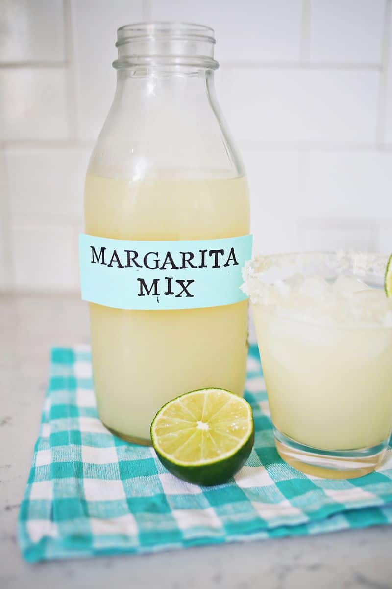 Margarita mix in a glass with a glass of margarita and a lime next to it