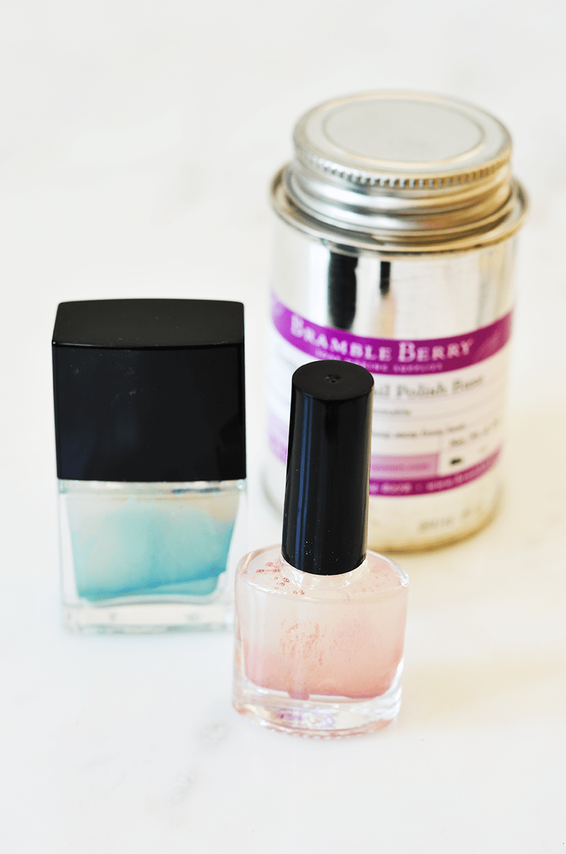 a jar of suspended nail polish base with 2 nail polish bottles in front of it