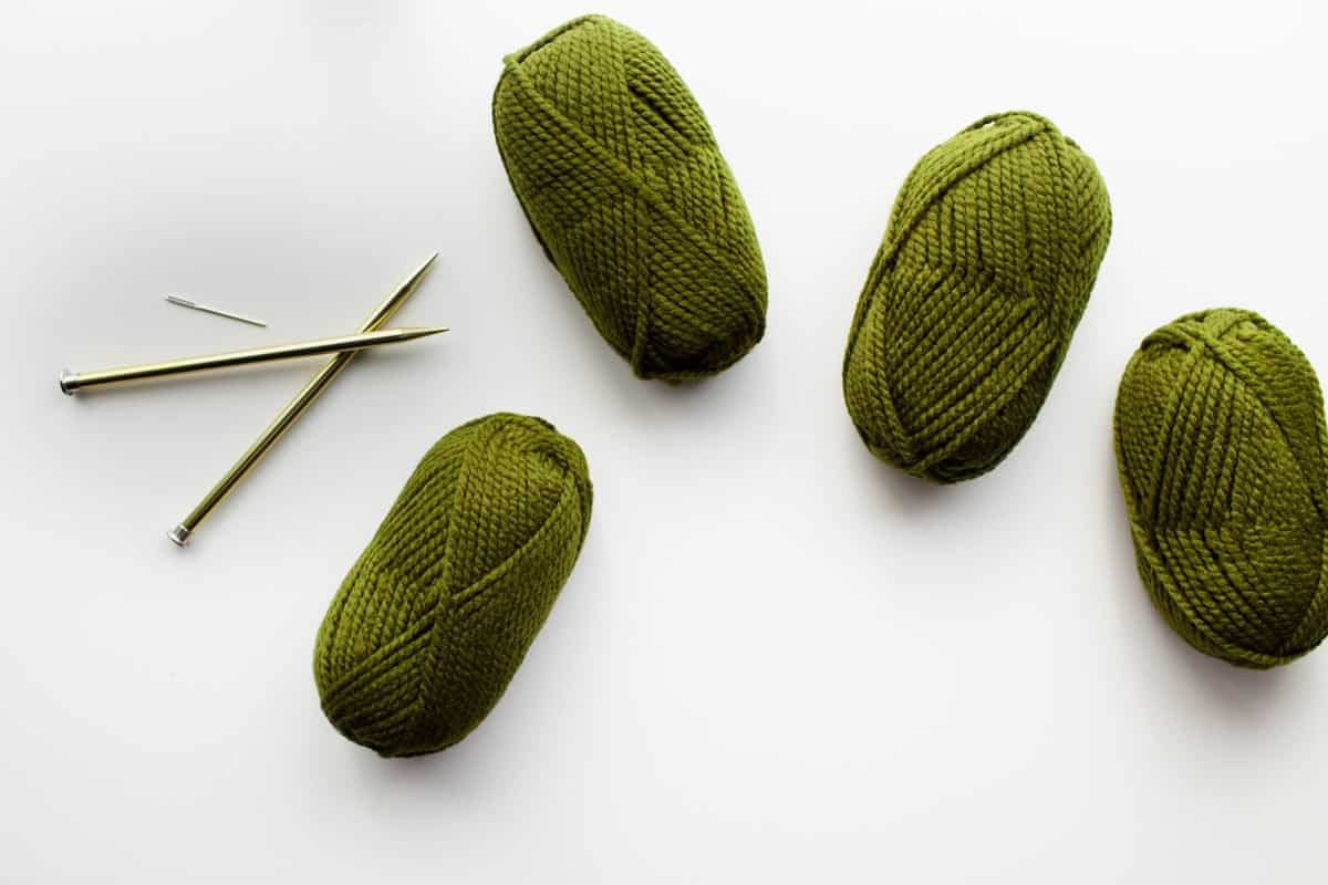4 bundles of green yarn and knitting needles