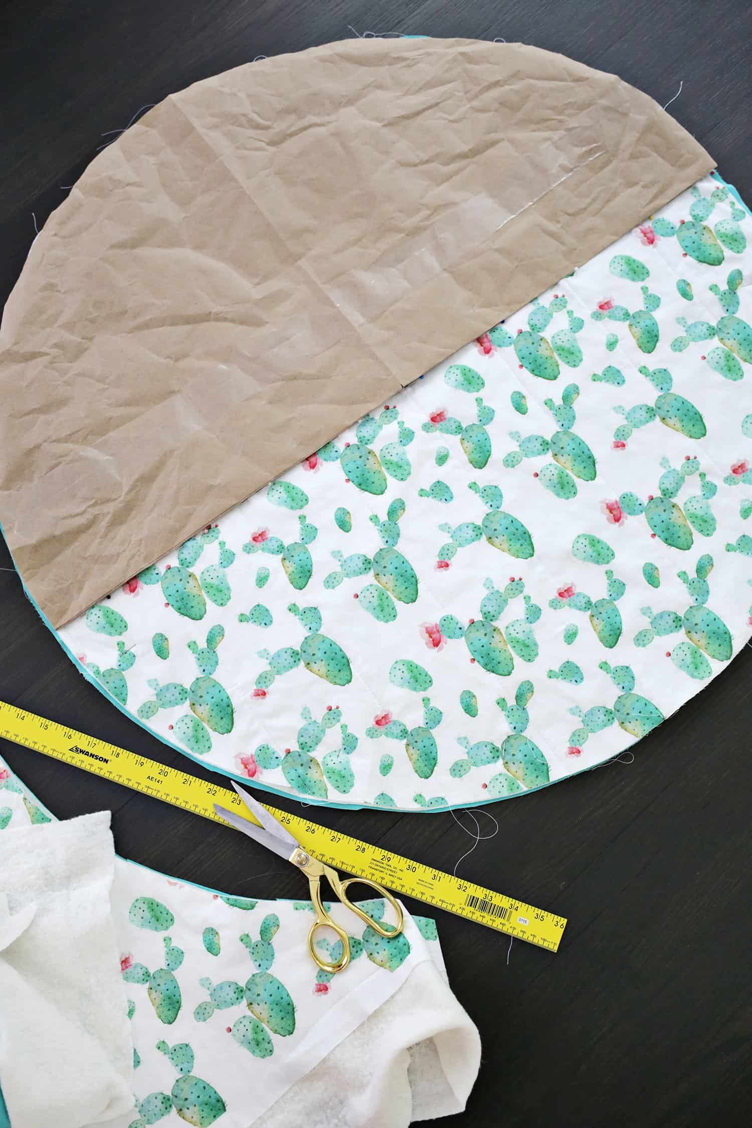 half a circle parchment paper on circle cut out of catcus fabric with yellow ruler and gold scissors