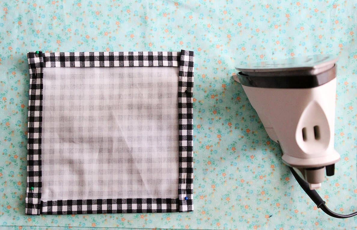 square piece of black and white checkered fabric with an iron next to it