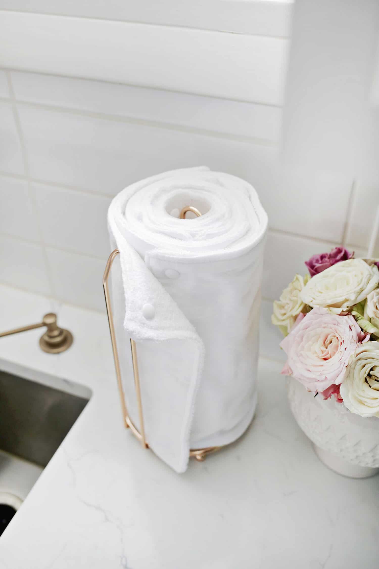 unpaper towel on a gold towel holder with a vase of flowers next to it