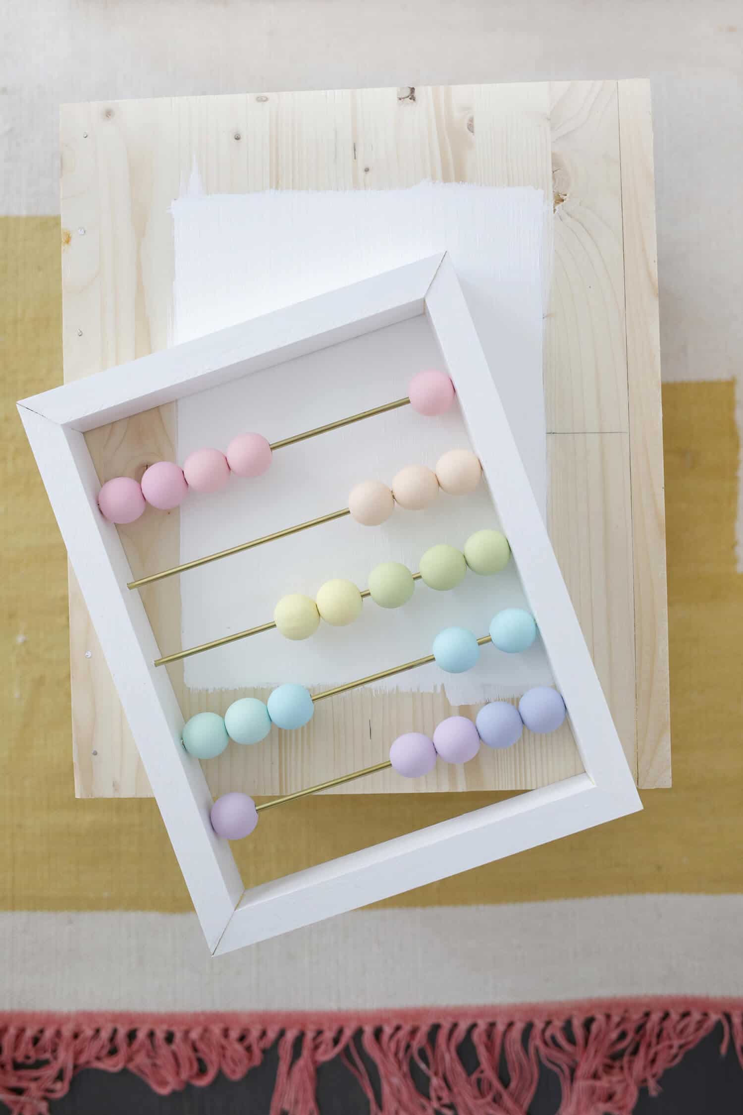 white frame with rods through it and colorful wooden circle balls on them