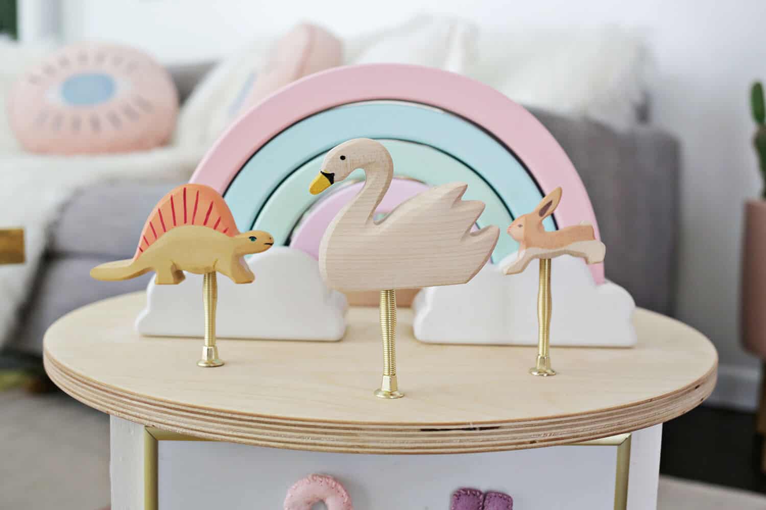 wooden dinosaur, wooden swan, wooden rabbit, and wooden rainbow on top of toddle activity center