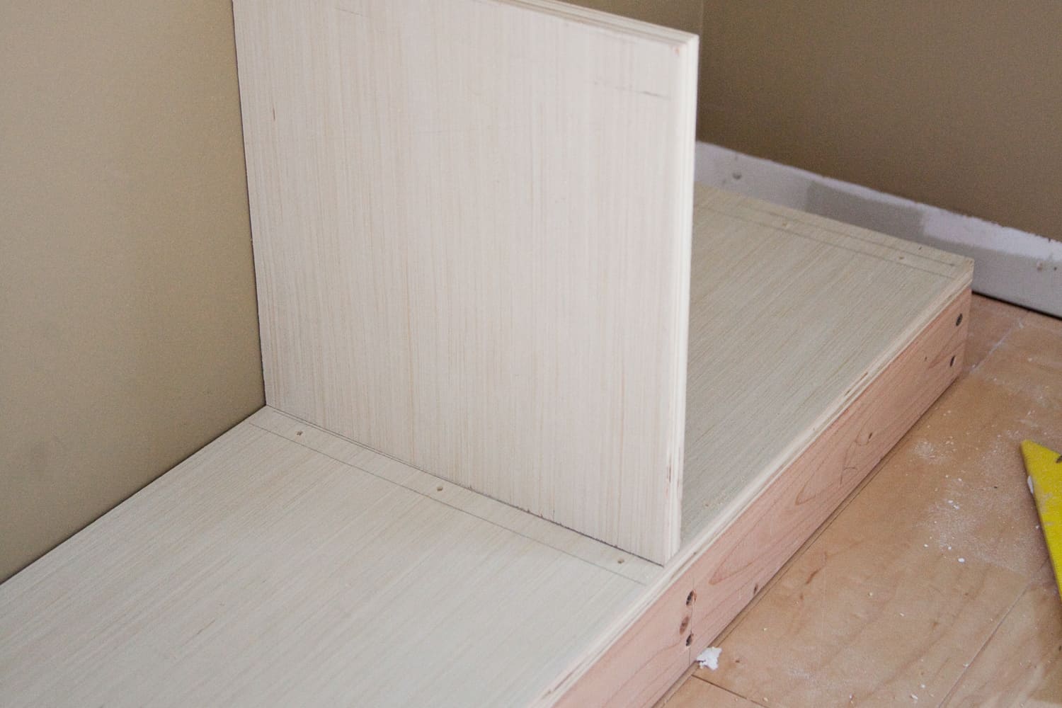 base of built-in Billy bookcase with piece of wood nailed into it on hardwood floor
