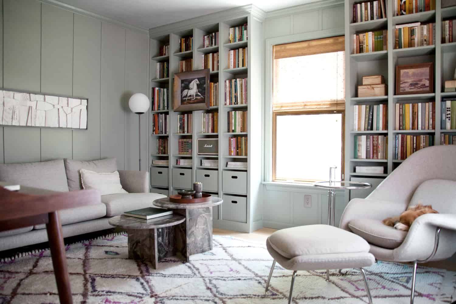 living room with built-in bookcases with a window in between, a gray couch, a gray chair, and a coffee table