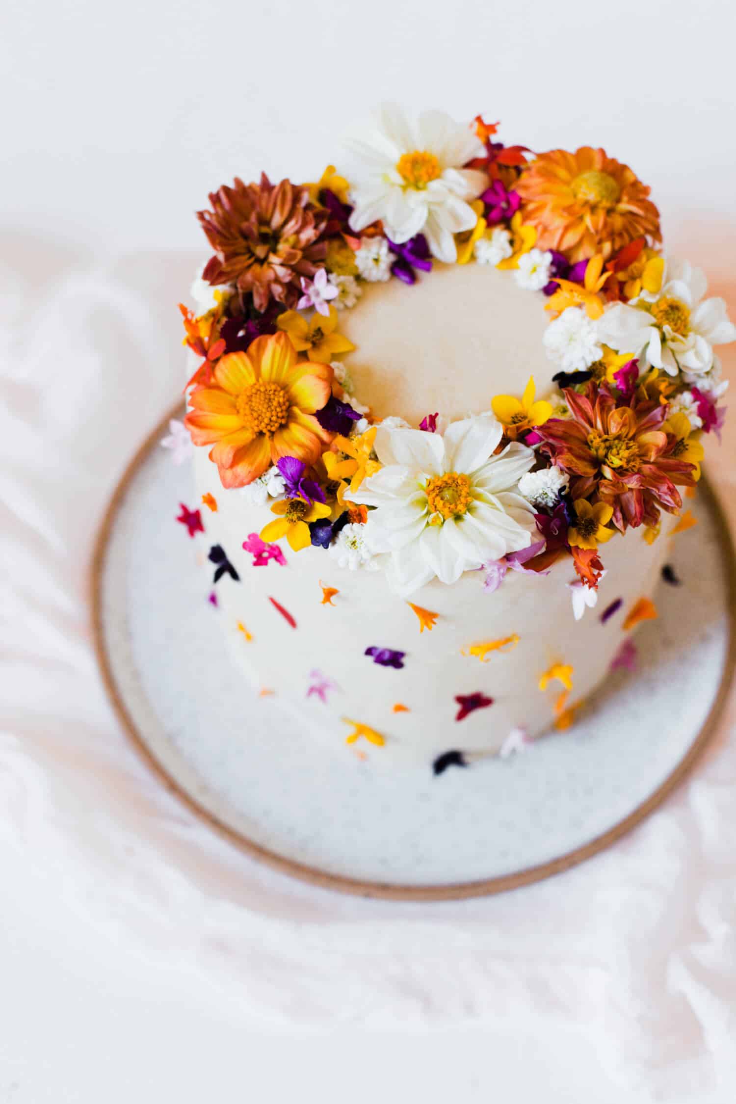 a white frosted cake with edible flowers on it