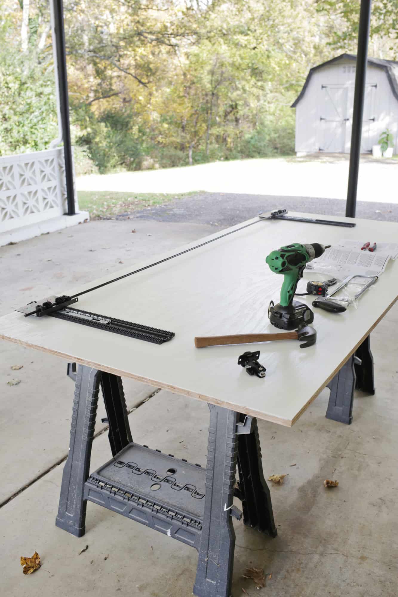 a big wooden board on 2 sawhorses with a drill, hammer, measuring tape, saw, and instructions on it