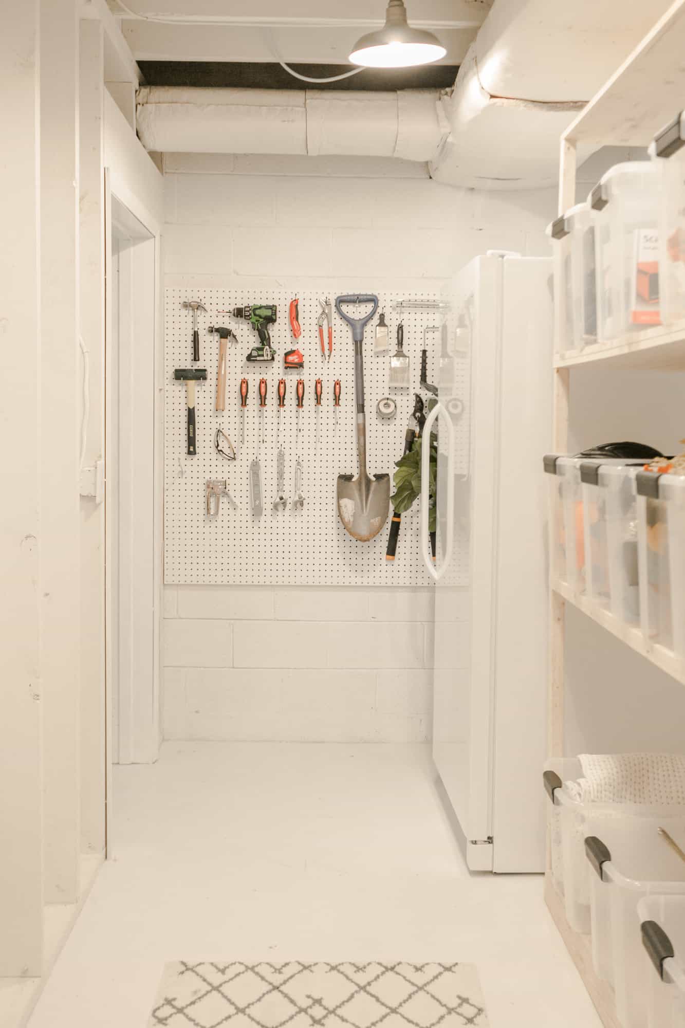 wall of the storage room with a white cork board hanging on the wall with tools hanging on it