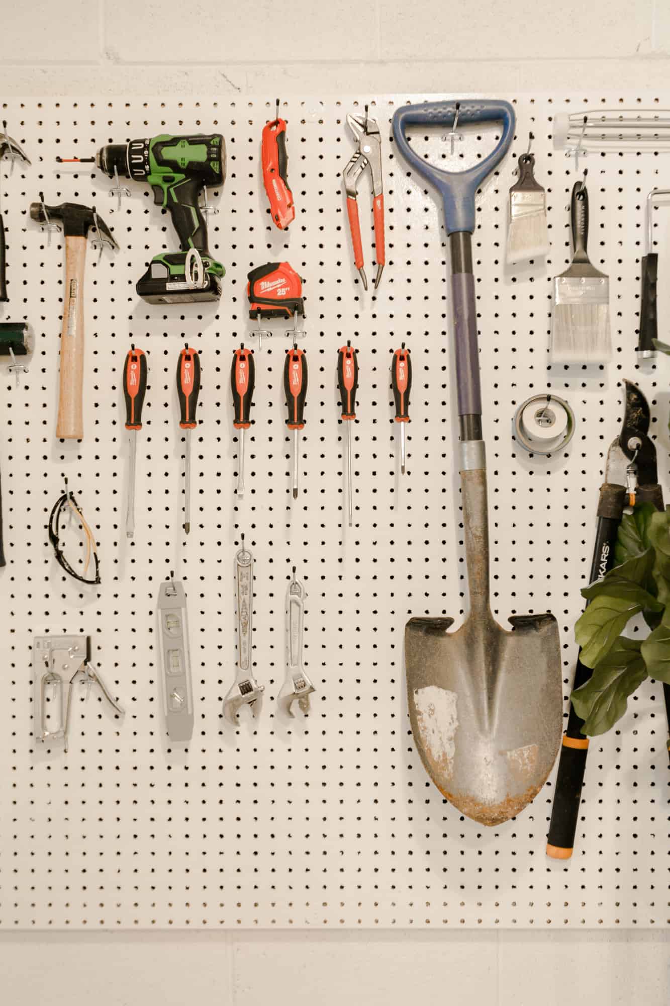close up of white corkboard with tools hanging on it