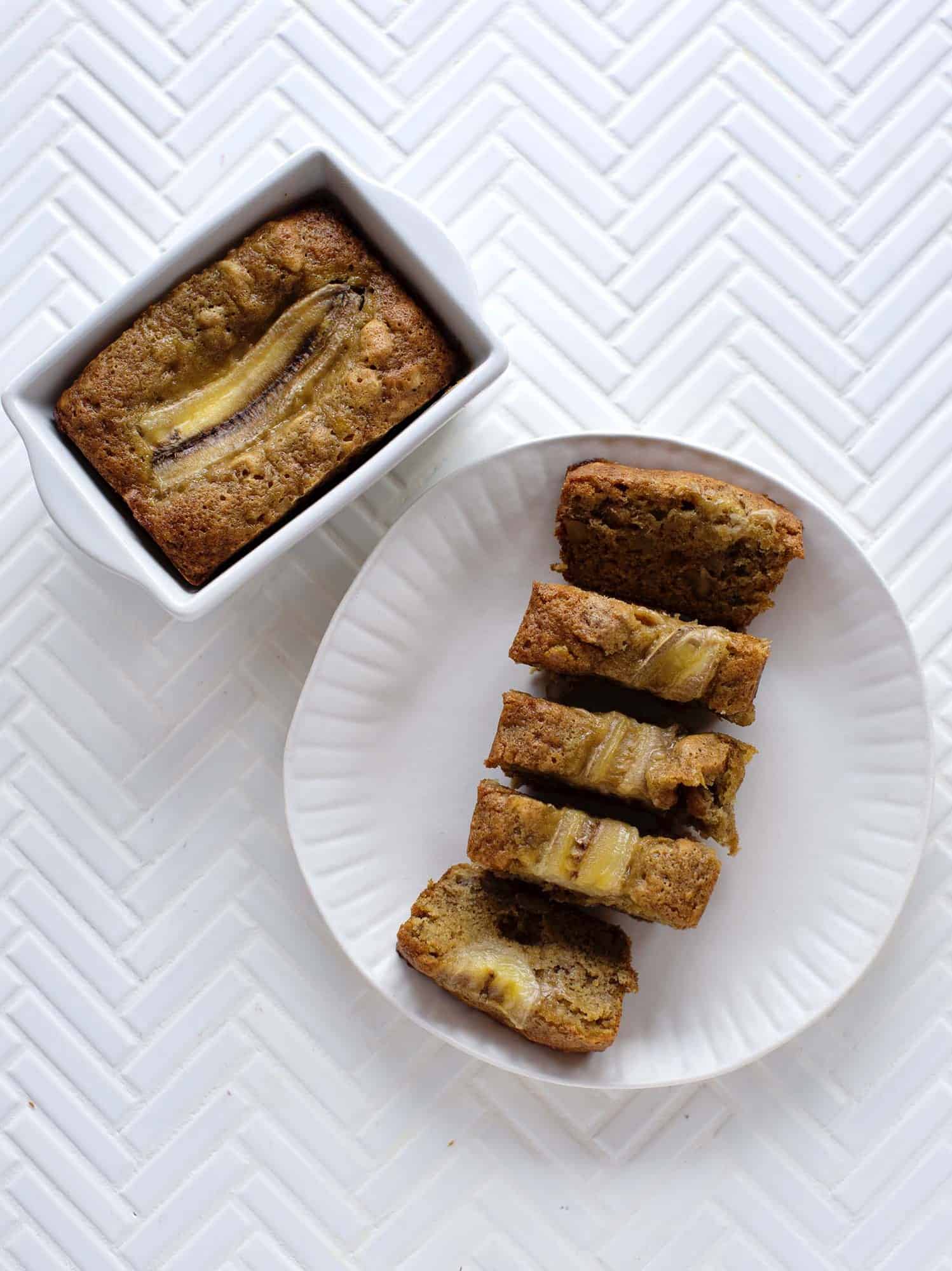 a loaf of banana bread in a dish and another loaf if banana bread cut into 5 sections on a plate