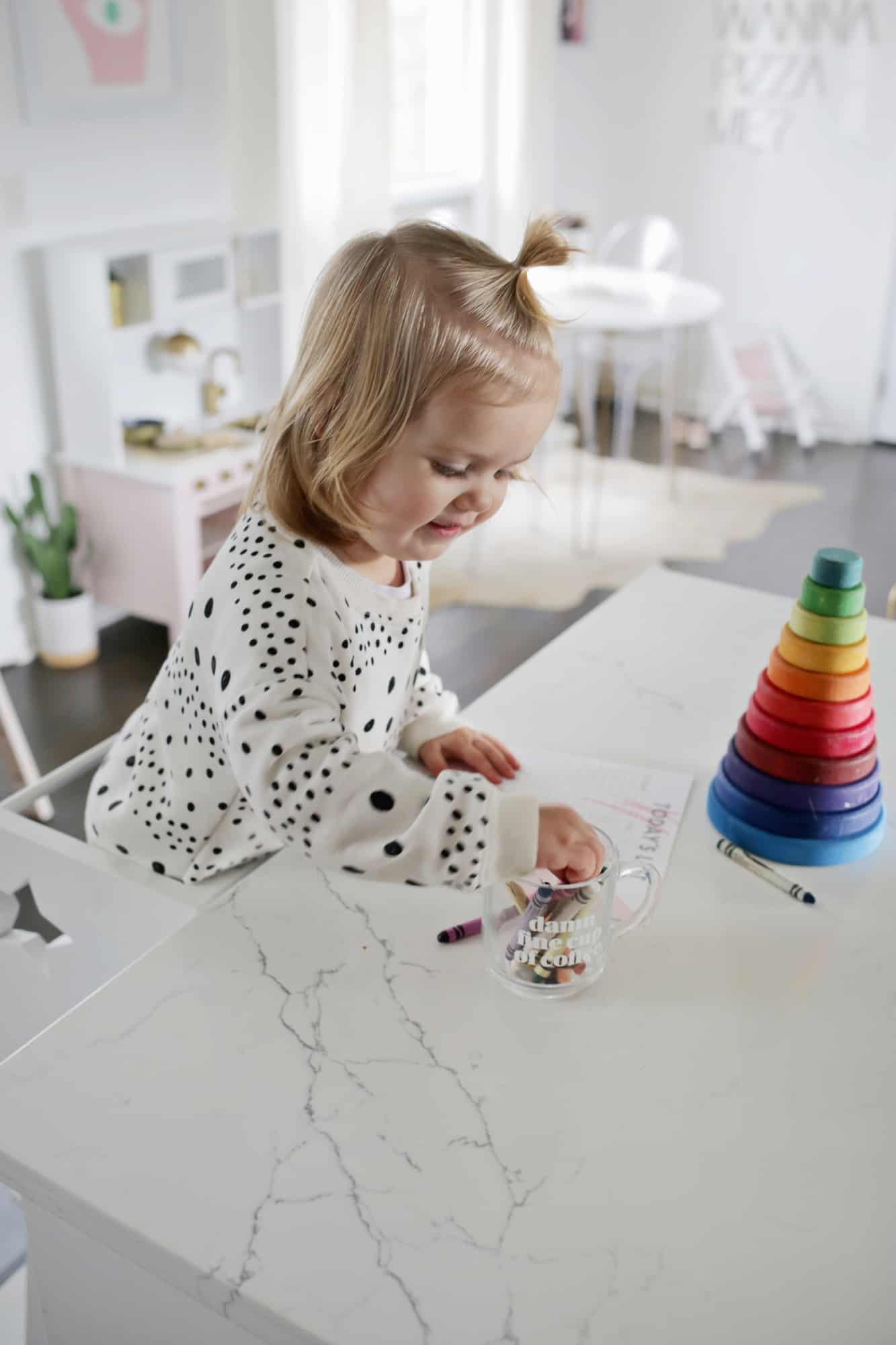 a toddler coloring on kitchen island while standing on star step stool