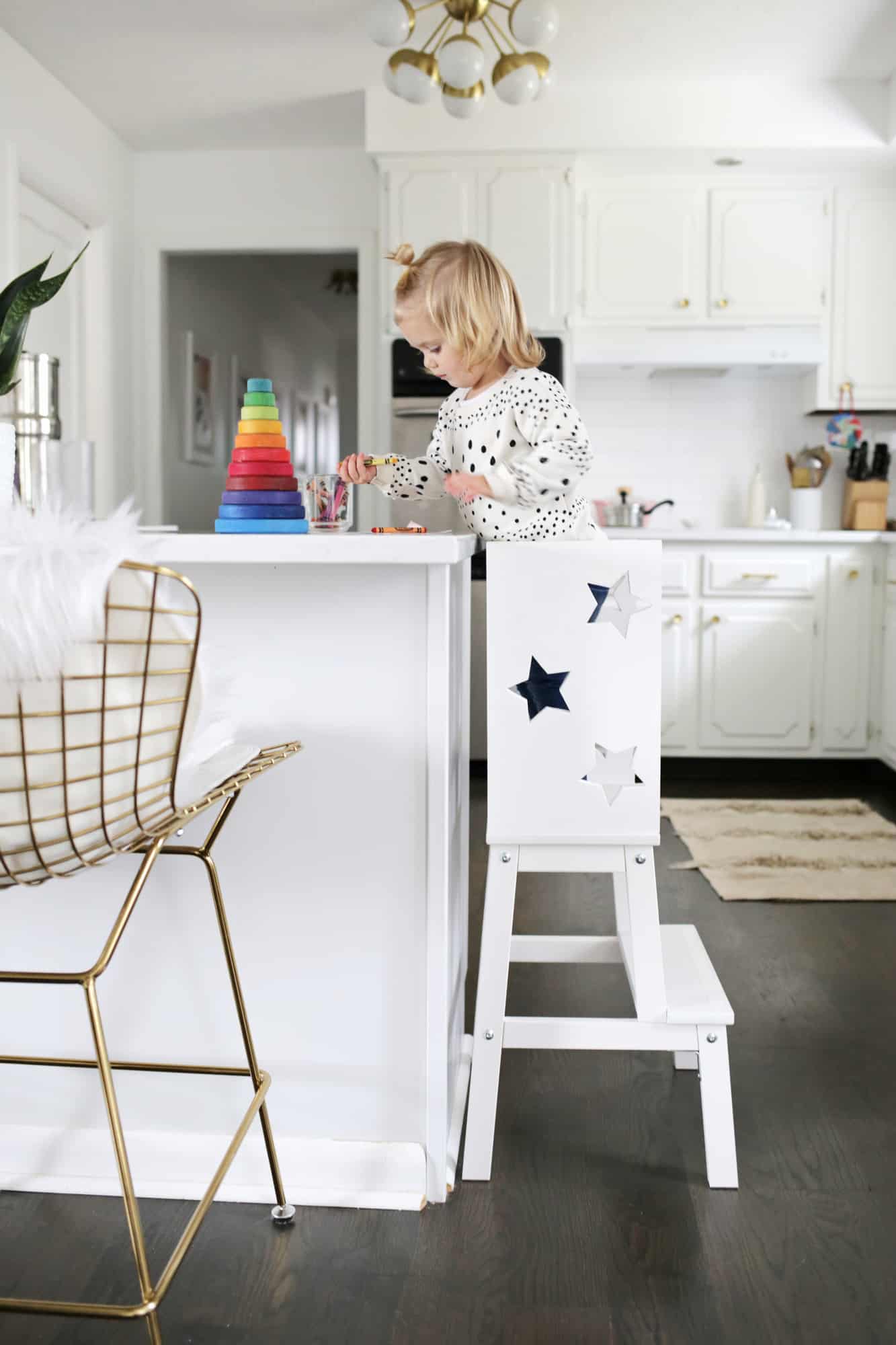 toddler on a star stool at a kitchen island playing with toys