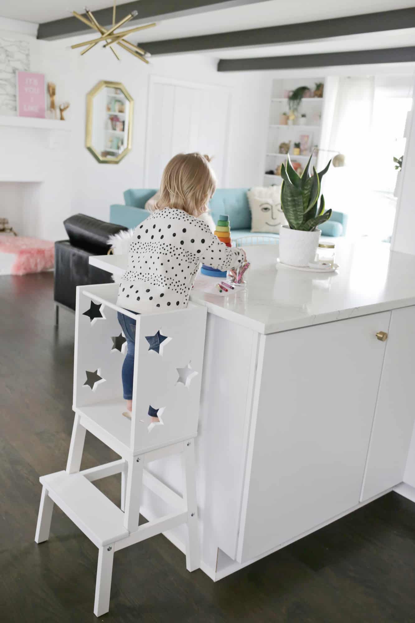 toddler standing on star step stool playing with toys on a kitchen counter