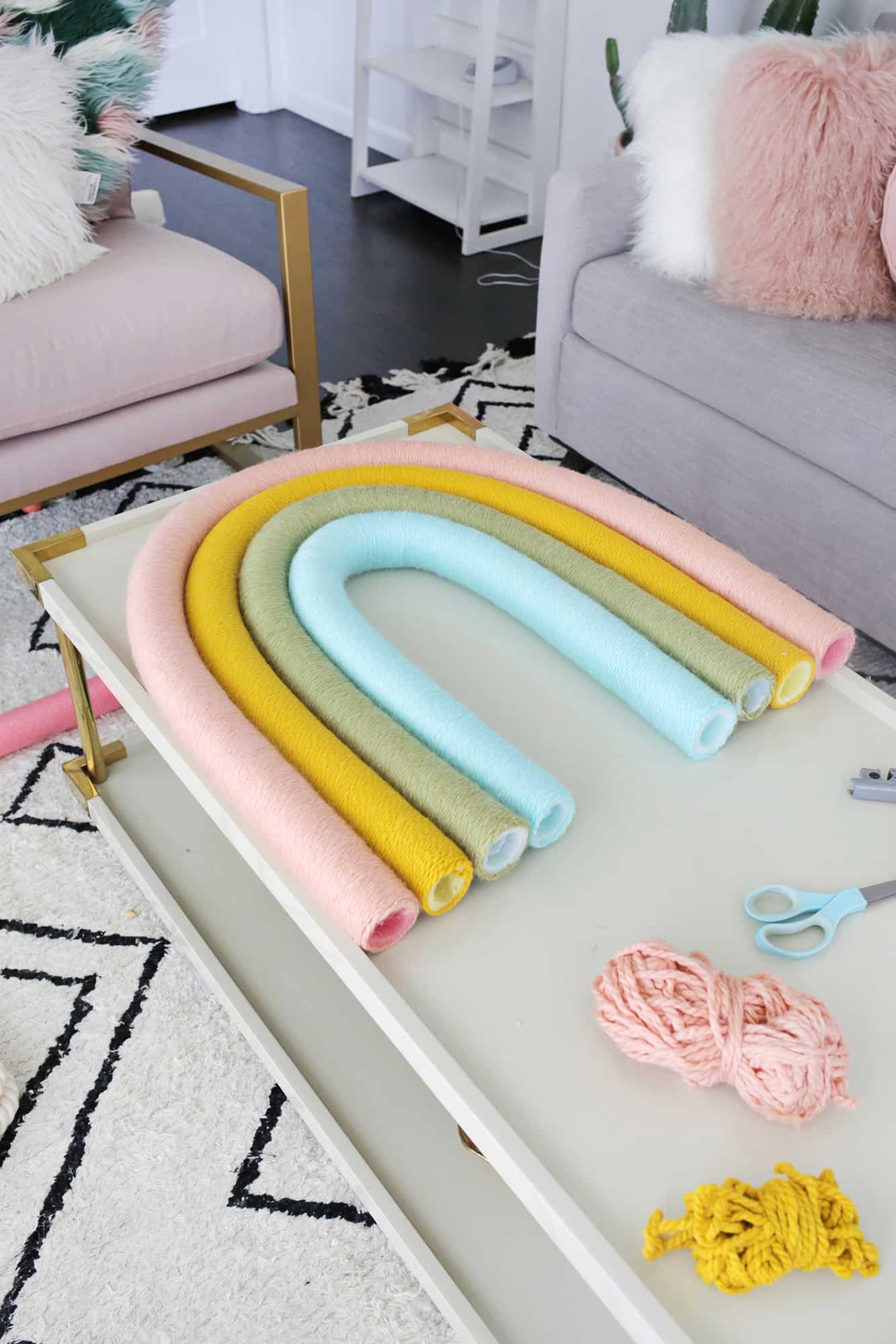 4 yarned wrapped pool noodles in rainbow shape on coffee table