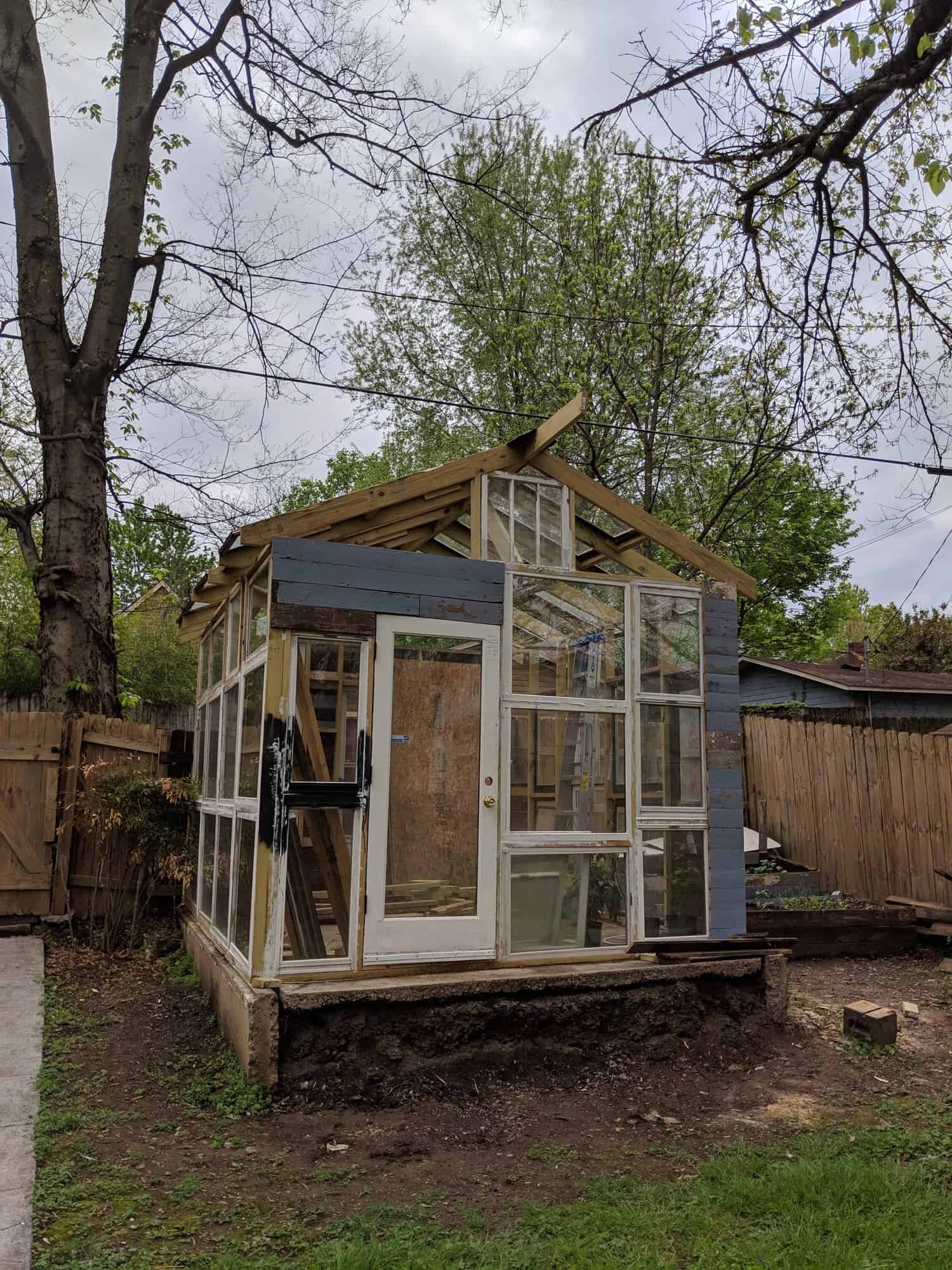 wooden frame of greenhouse with old windows and a door in it