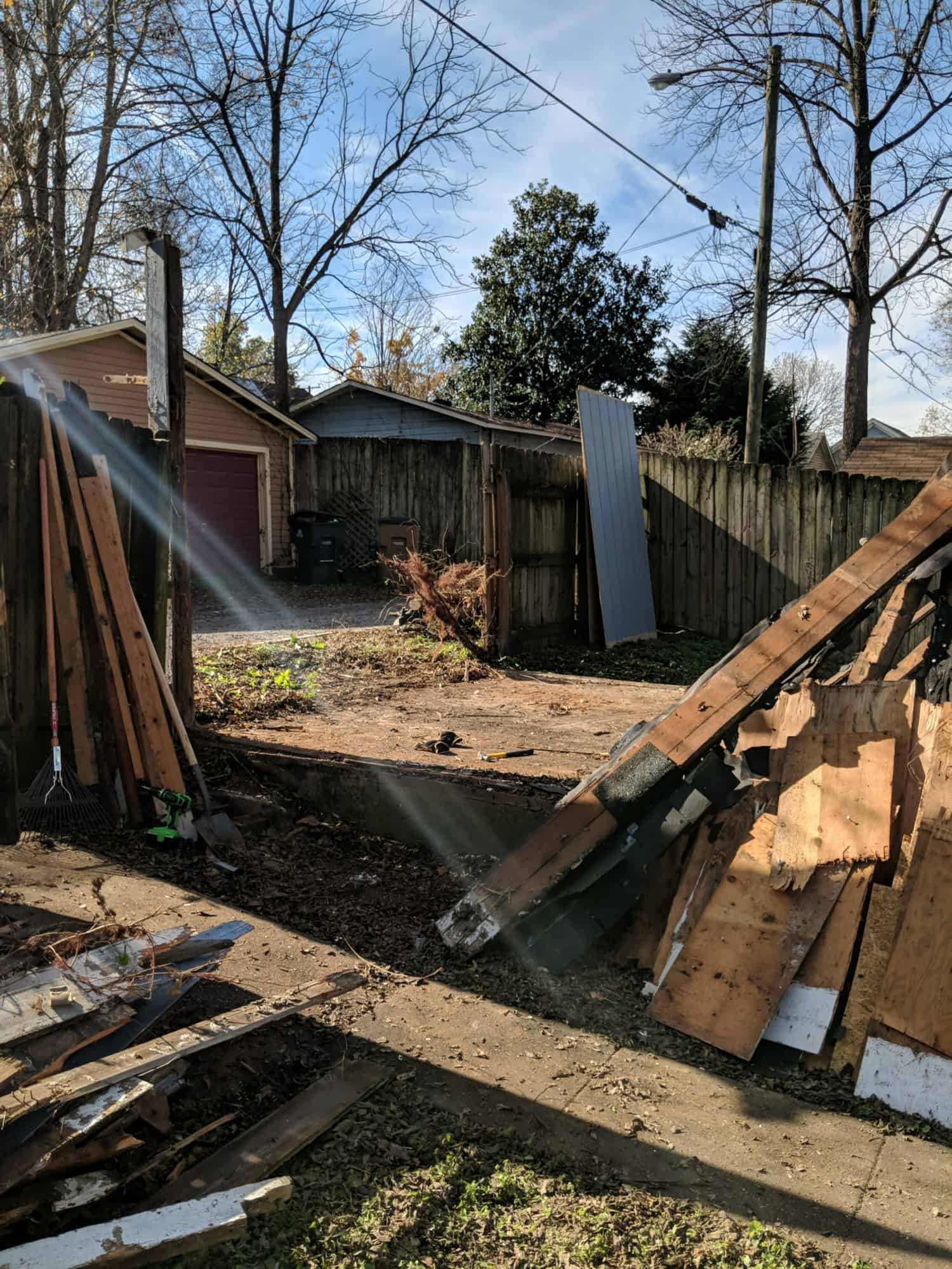torn down blue shed by a wooden fence in a backyard