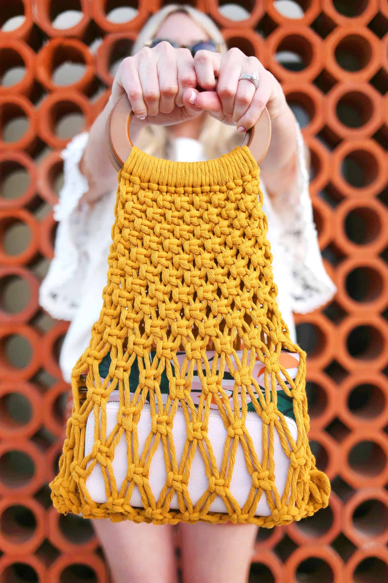 a woman holding out the yellow macrame handbag in front of her