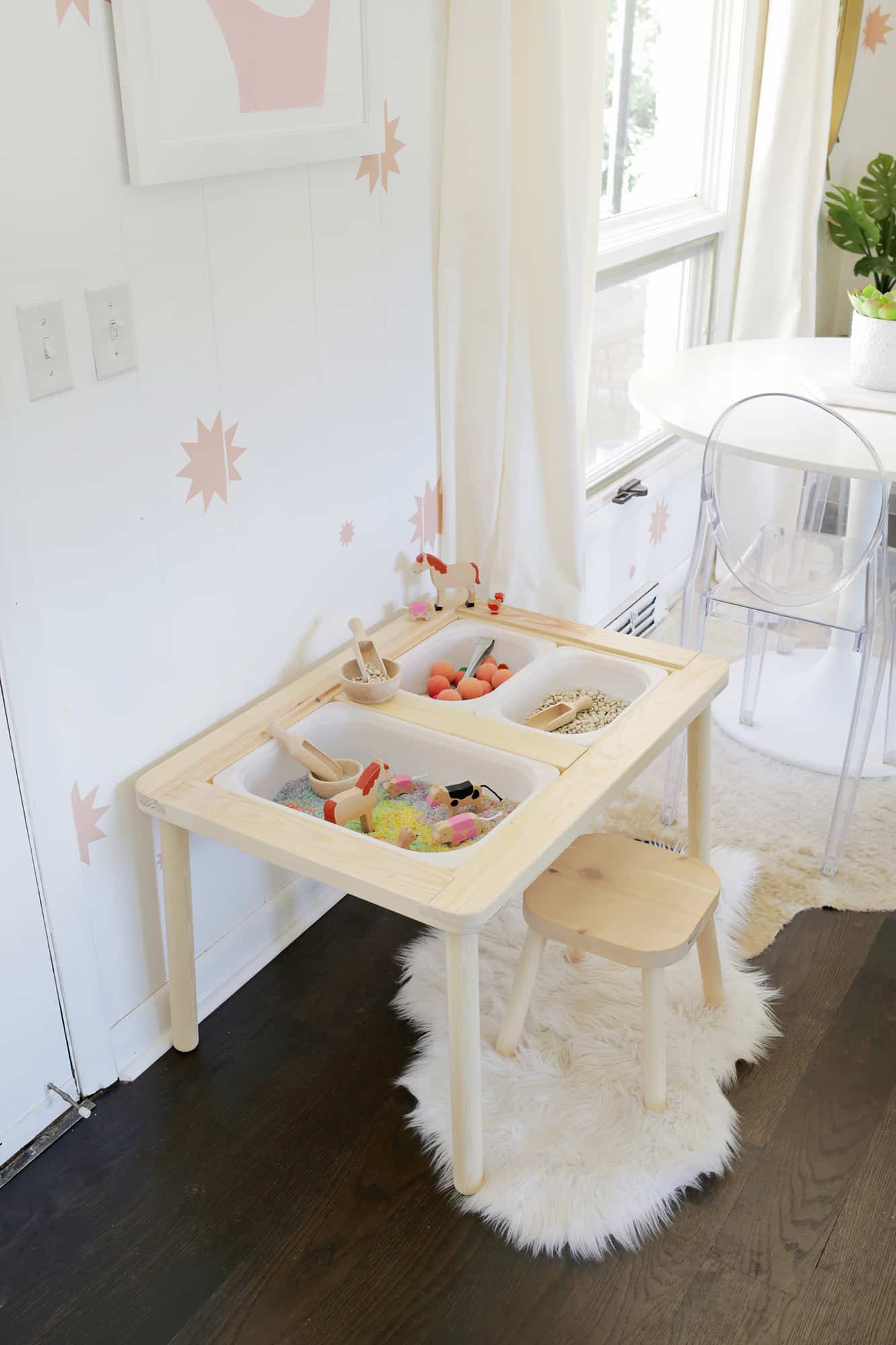 wooden sensory table with a small wooden stool on a white rug