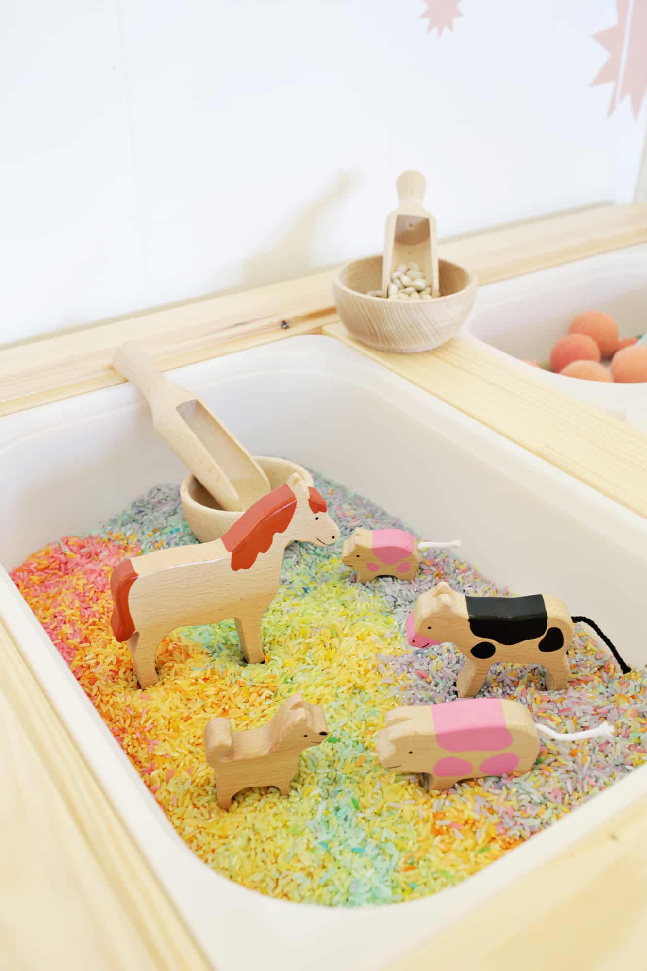 wooden animals in the bin of colorful rice with a wooden scoop and a wooden bowl