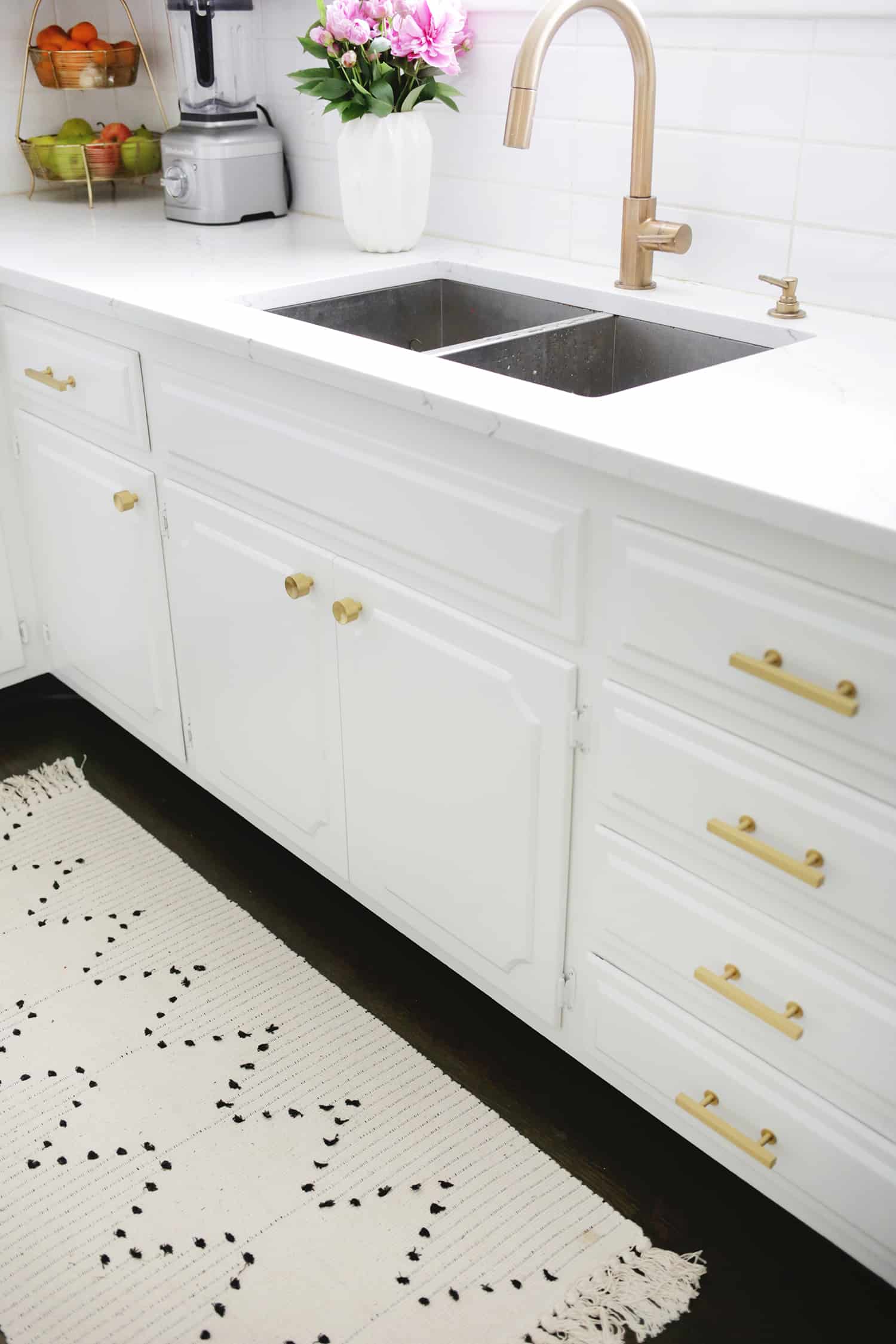 white kitchen with gold handles and a sink with a gold facuet