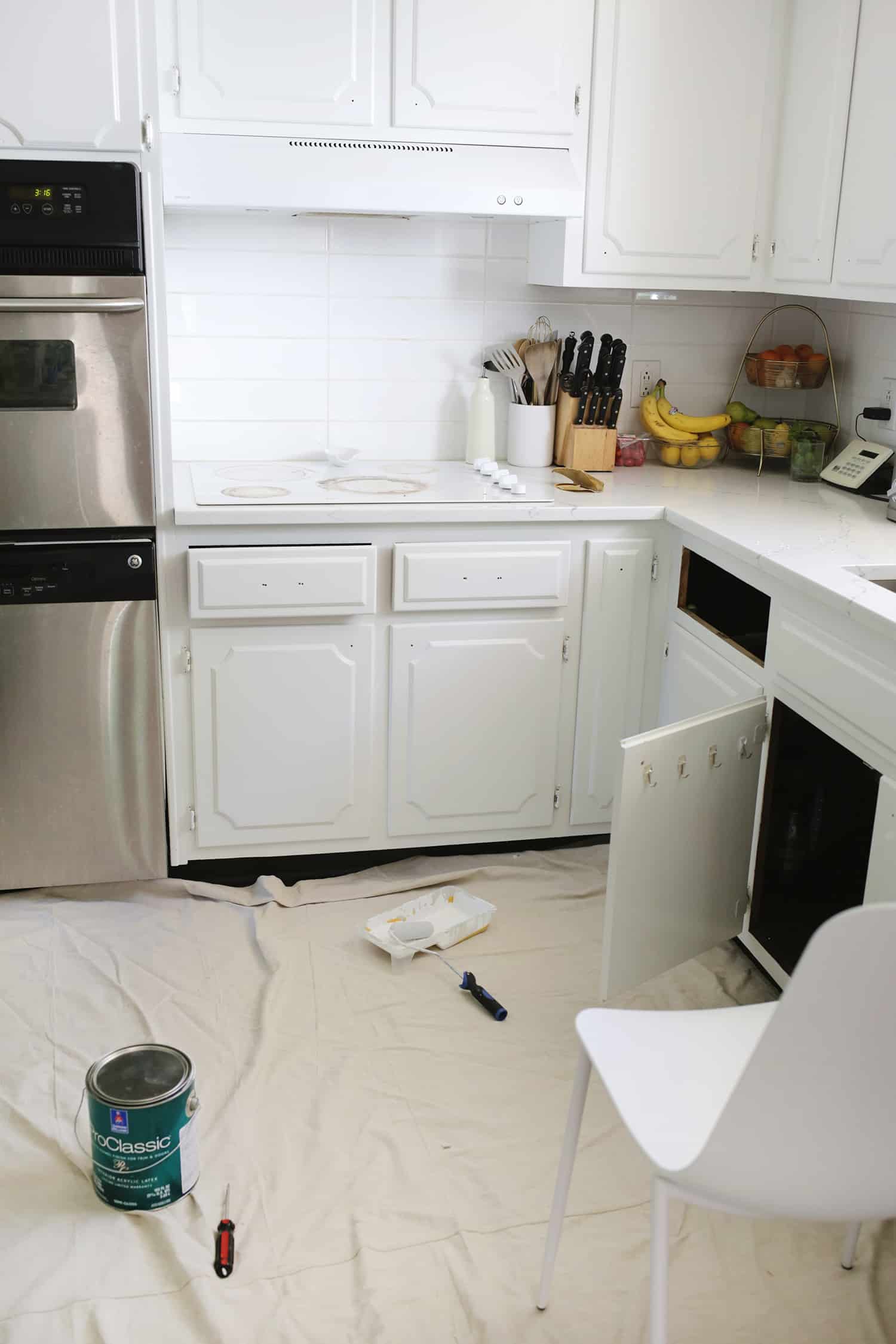 vitt kök utan handtag på skåp och en låda saknas med en skåpdörr öppen