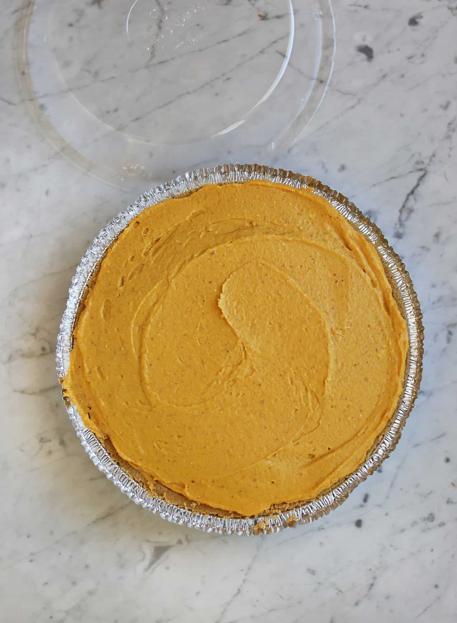 pumpkin puree on a graham cracker pie crust in aluminum pie pan