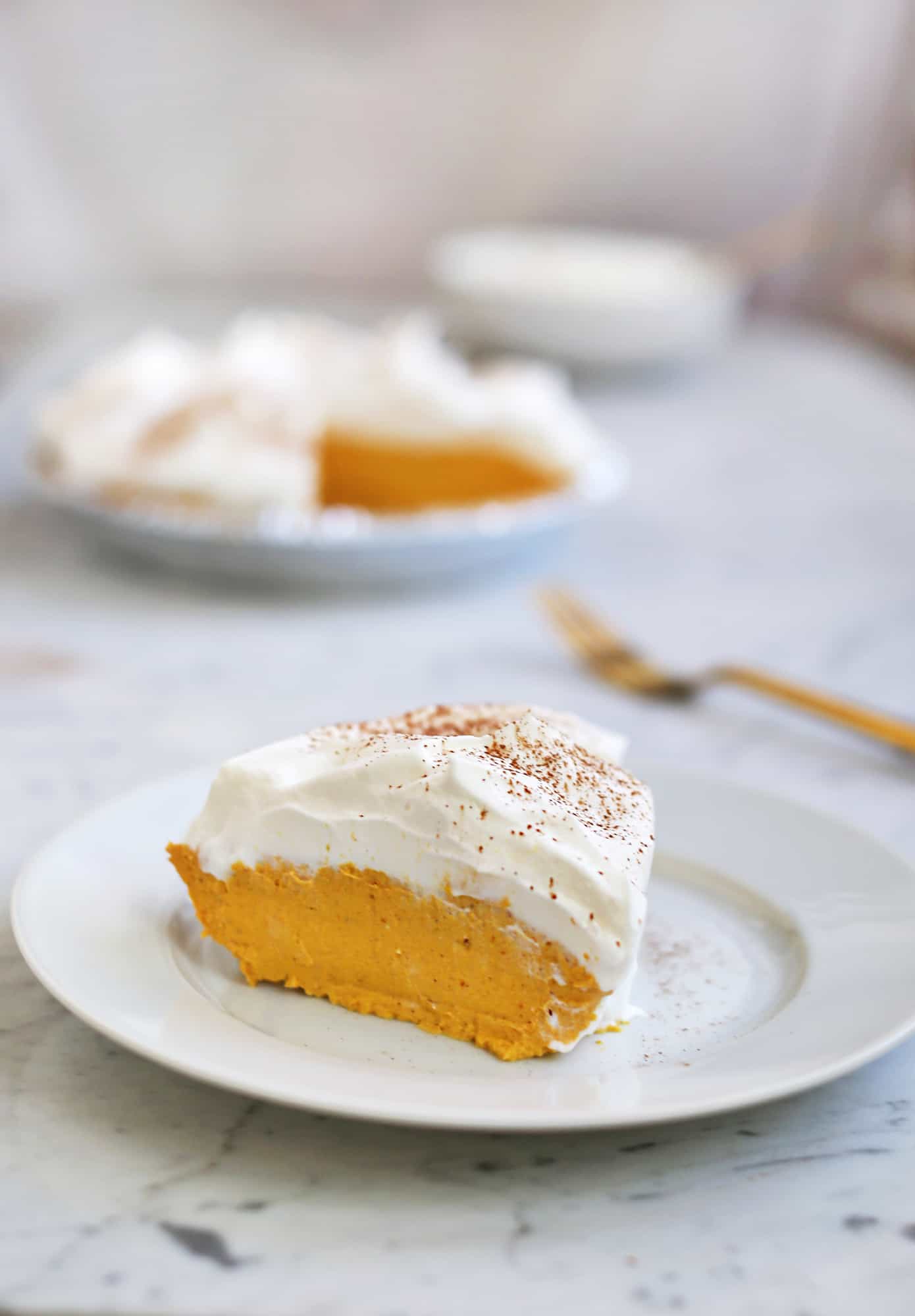 close up of slice of no bake pumpkin pie on white plate