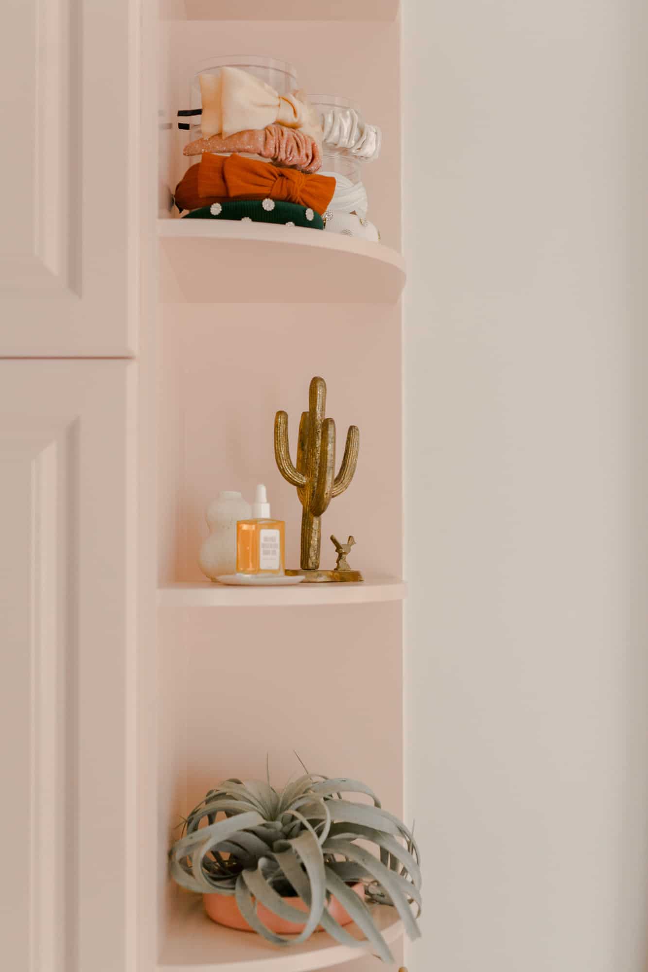 pink corner shelves with a plant, decor, and bows on them
