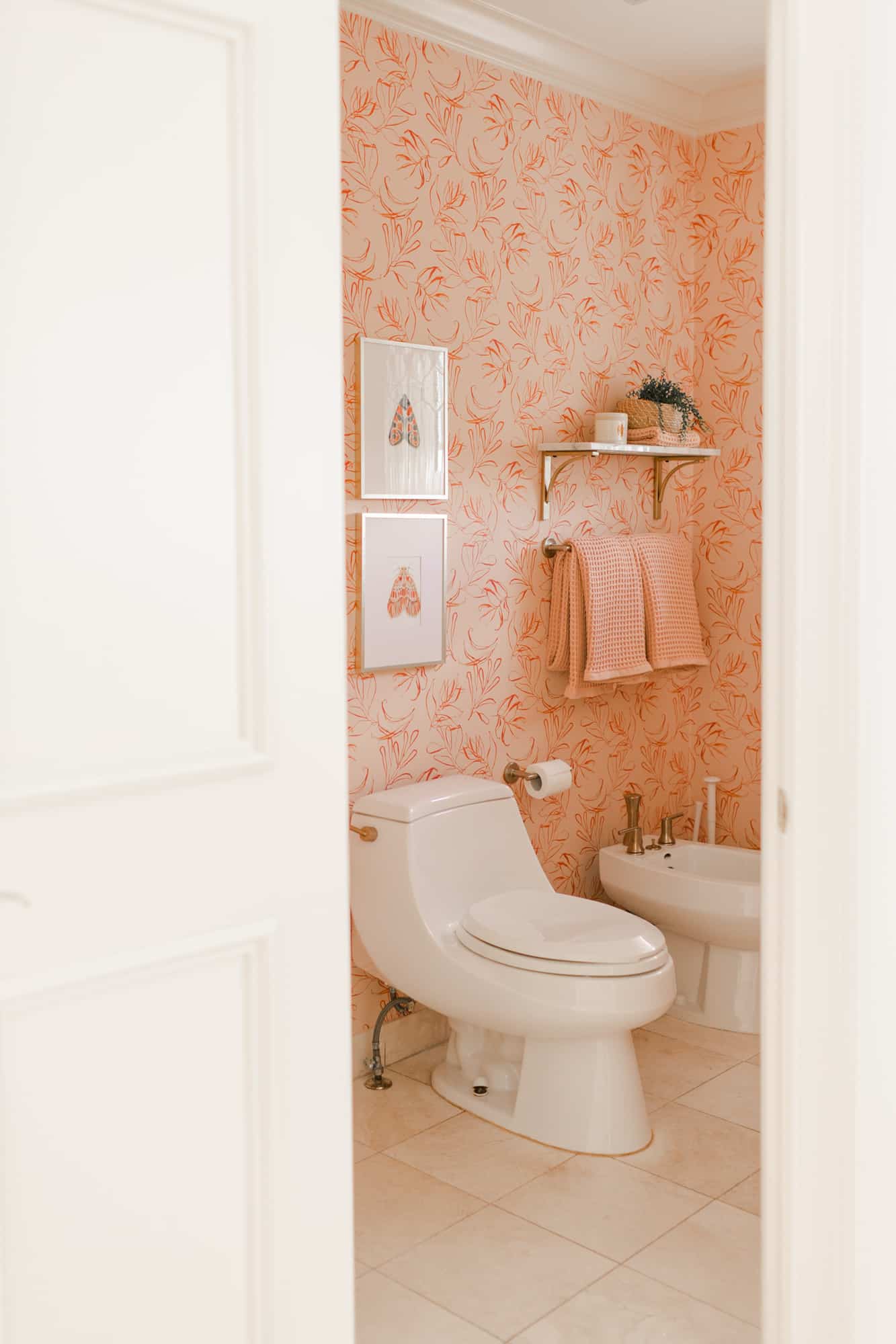 pink with flower wallpaper in a bathroom wiht a toilet and bidet