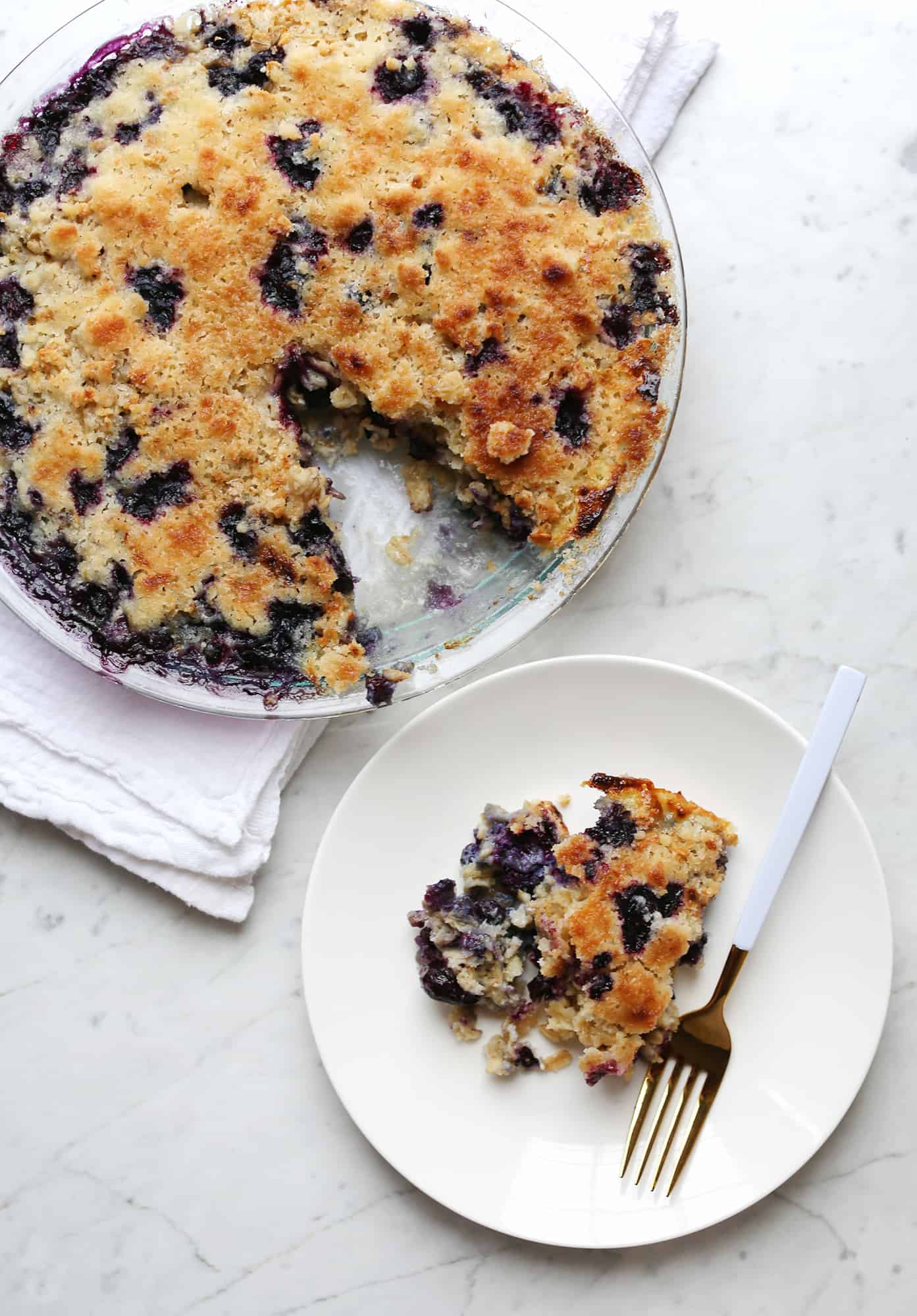 Overnight baked blueberry muffin oatmeal with a piece taken out on a plate with a fork