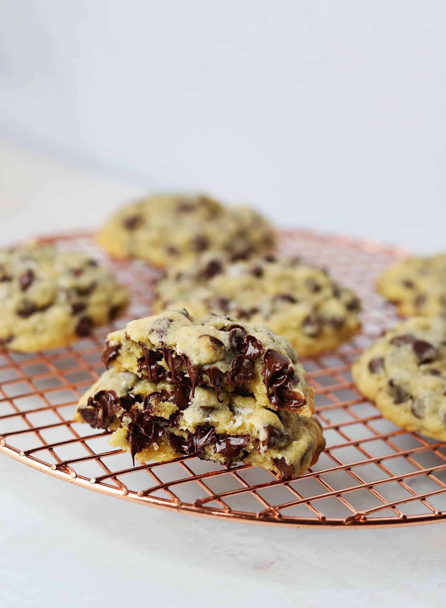 oversized soft center chocolate chip cookies on a cooling rack with one cookie cut in half