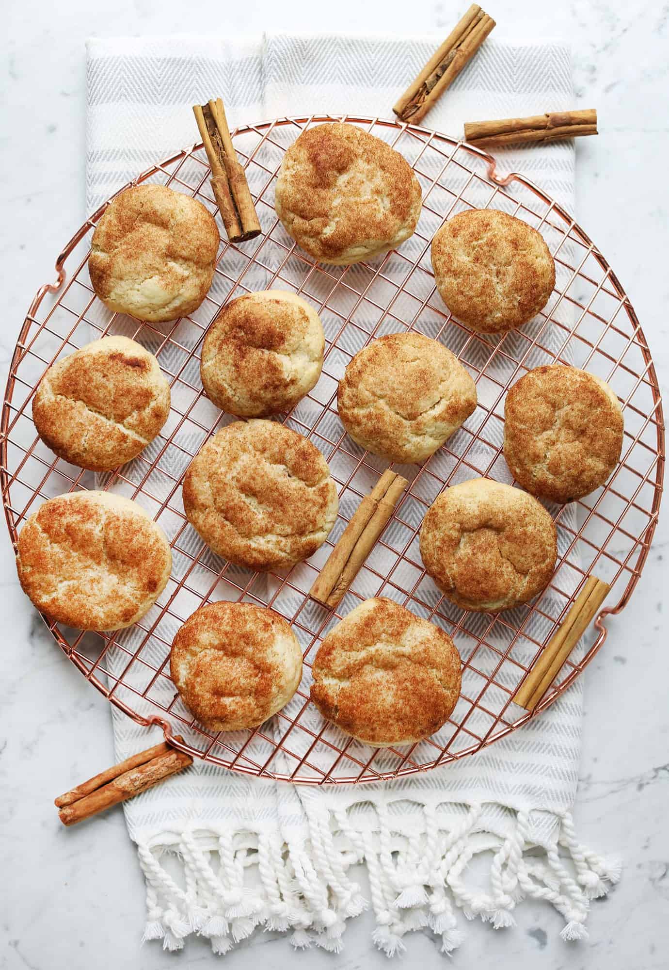 soft chewy snickdoodles on a cooling rack with cinnamon stick around it