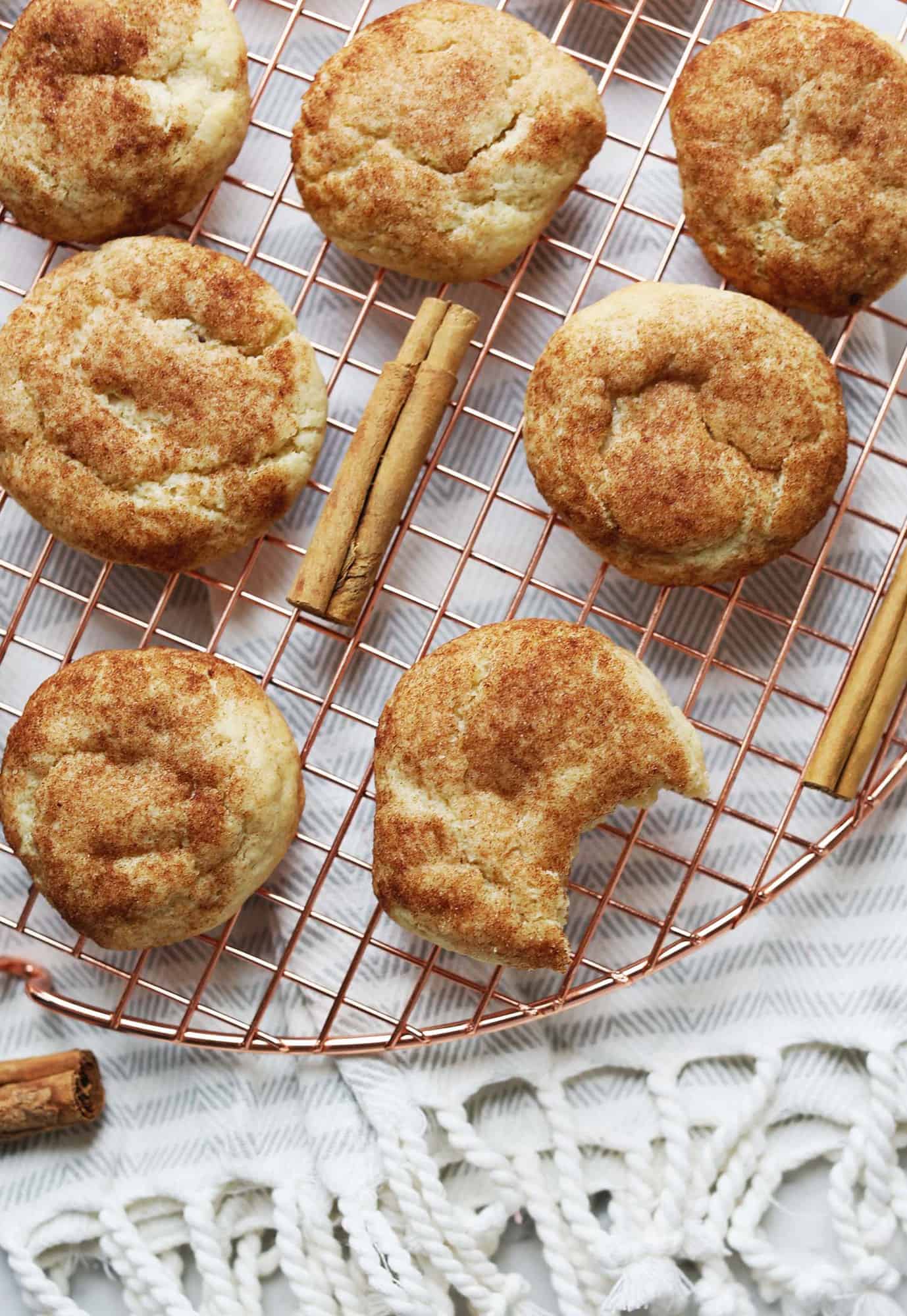 soft chewy snickdoodles on a cooling rack with one cookie having a bite taken out of it