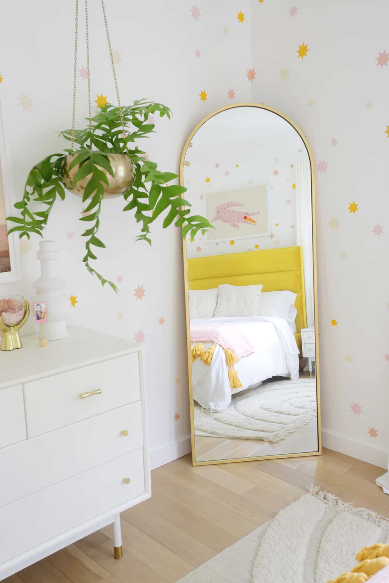 mirror with reflection of bedframe and hanging plant next to it