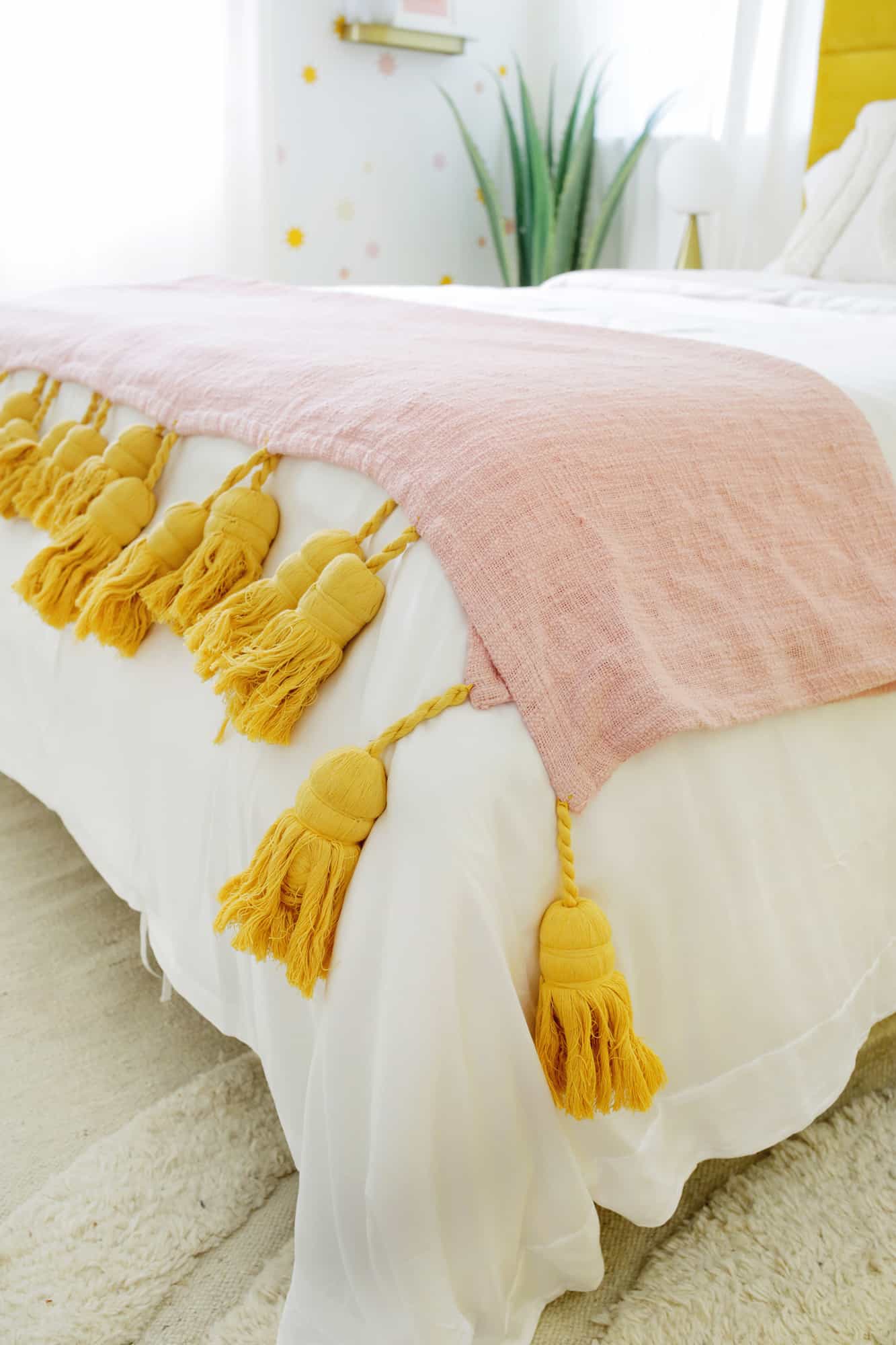 close up of throw blanket on bed with large tassels 