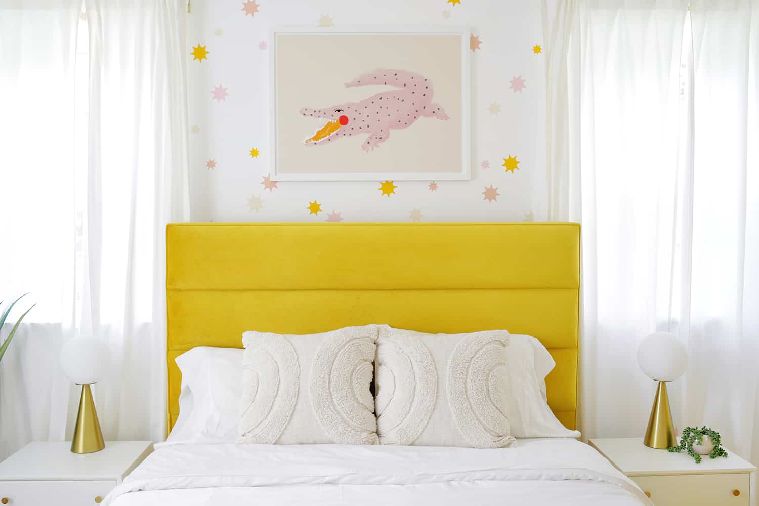 yellow velvet bed with throw pillows and alligator print above it