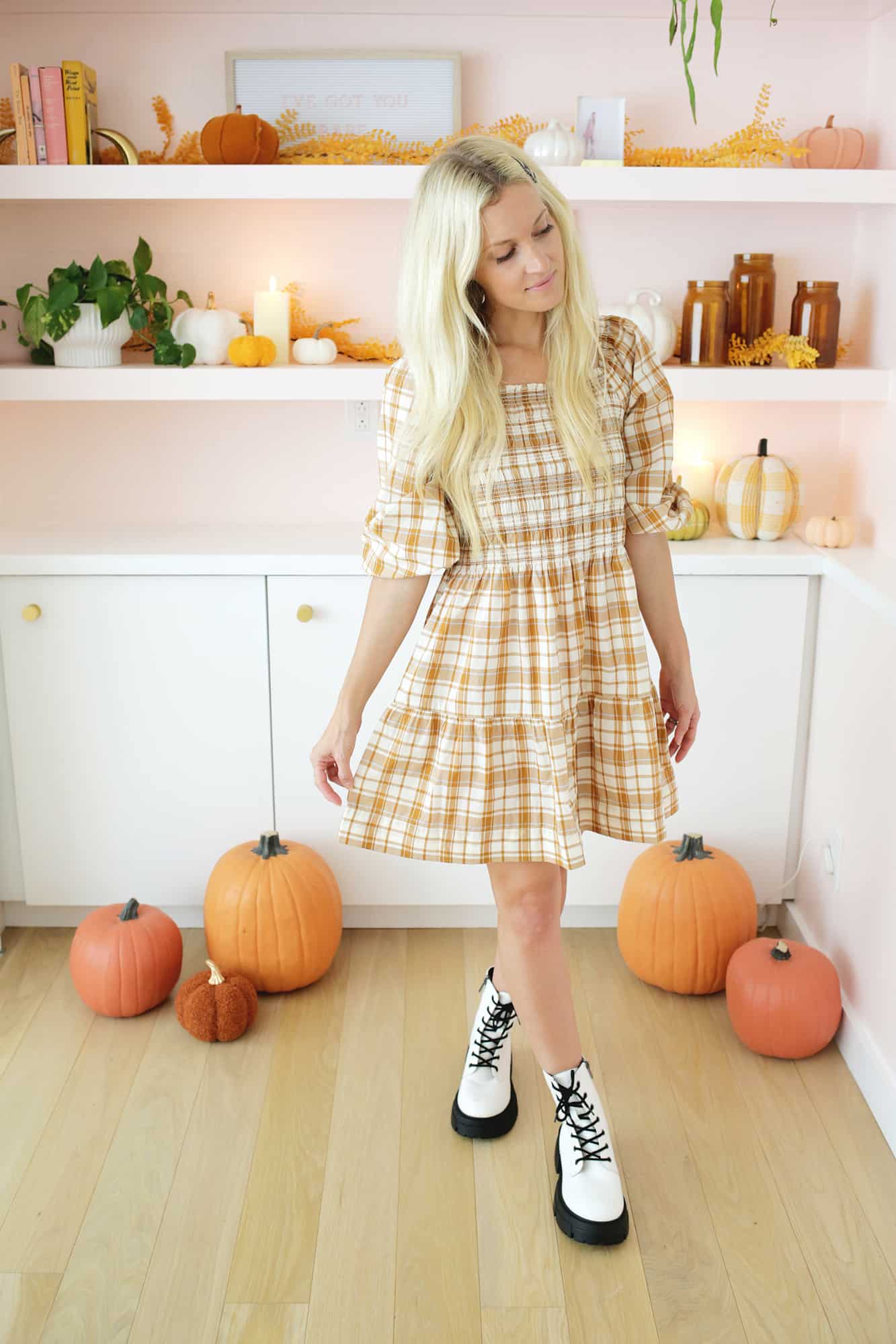 women wearing a plaid dress and boots in front of fall styled bookshelf