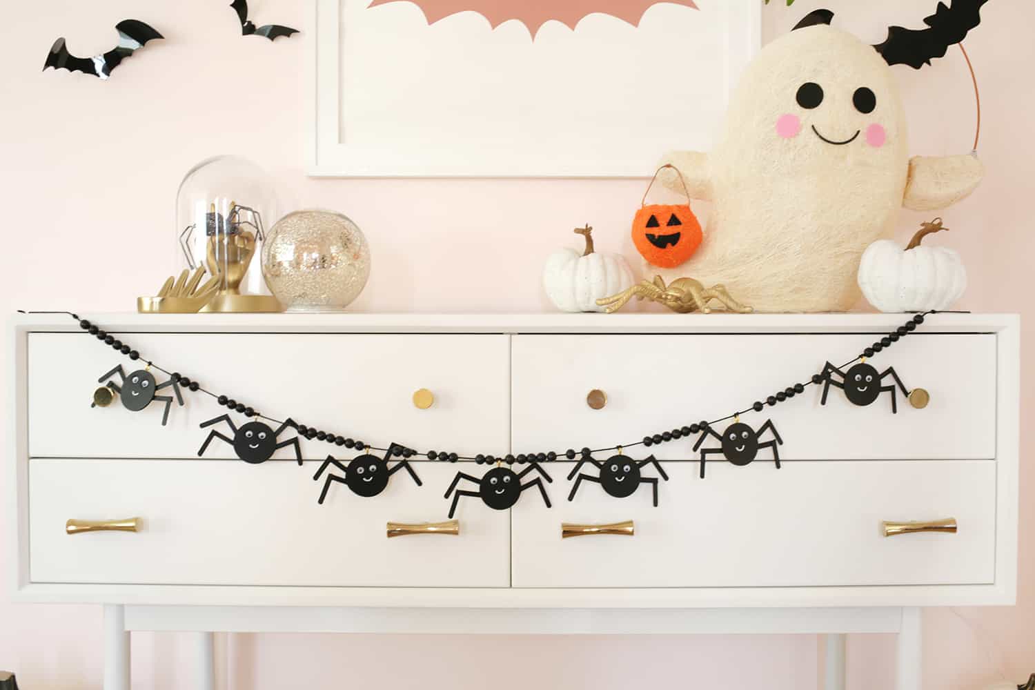 wooden spider garland strung across a console table decorated with pumpkins
