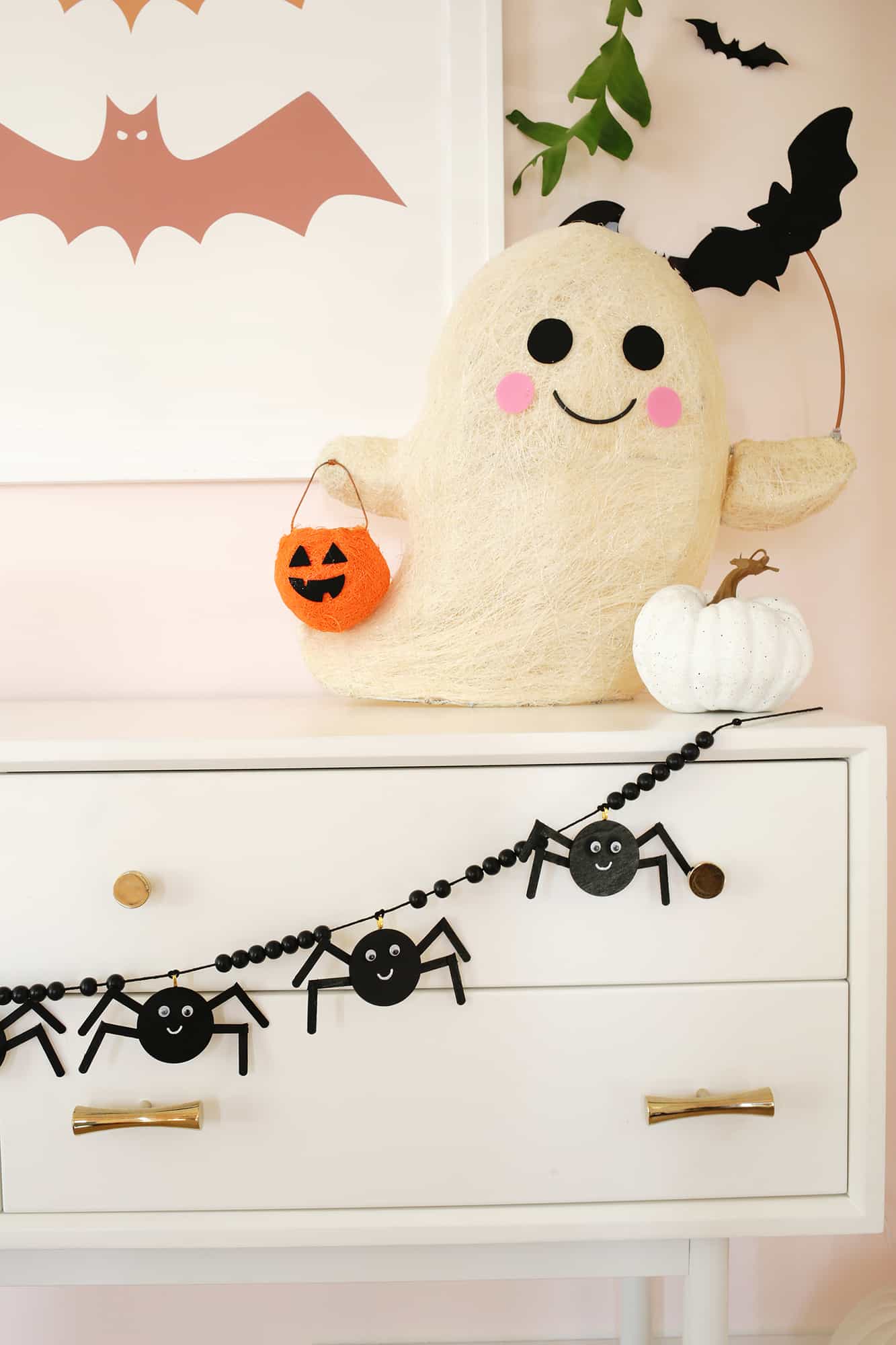 wooden spider garland strung across a console table decorated with pumpkins