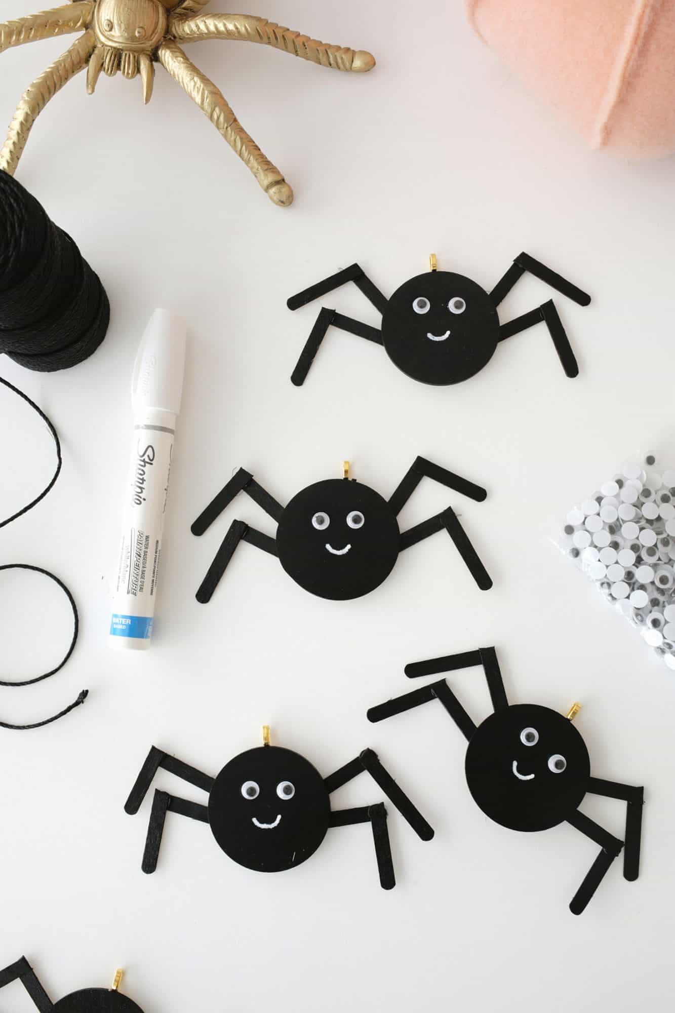 wooden spiders painted black with google eyes and smiley faces drawn on