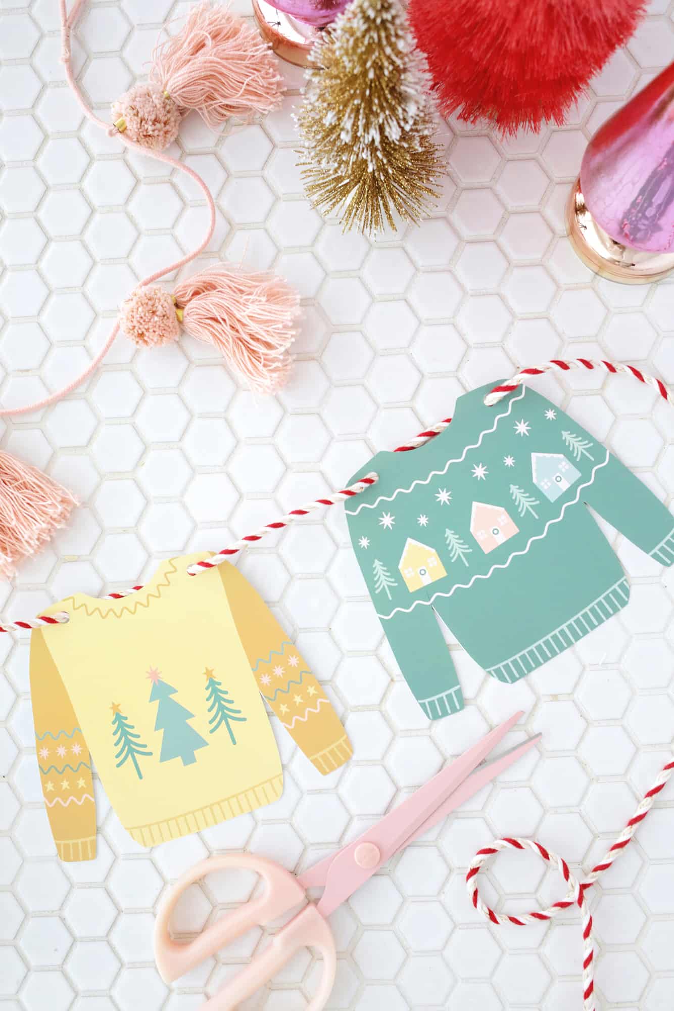 paper Christmas sweaters with a red and white yarn through punched holes