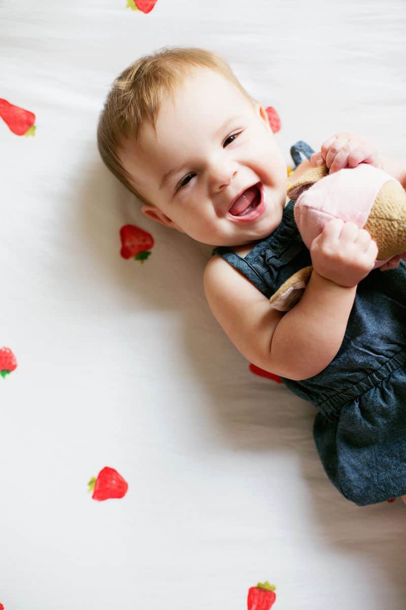 baby laying on strawberry printed sheets