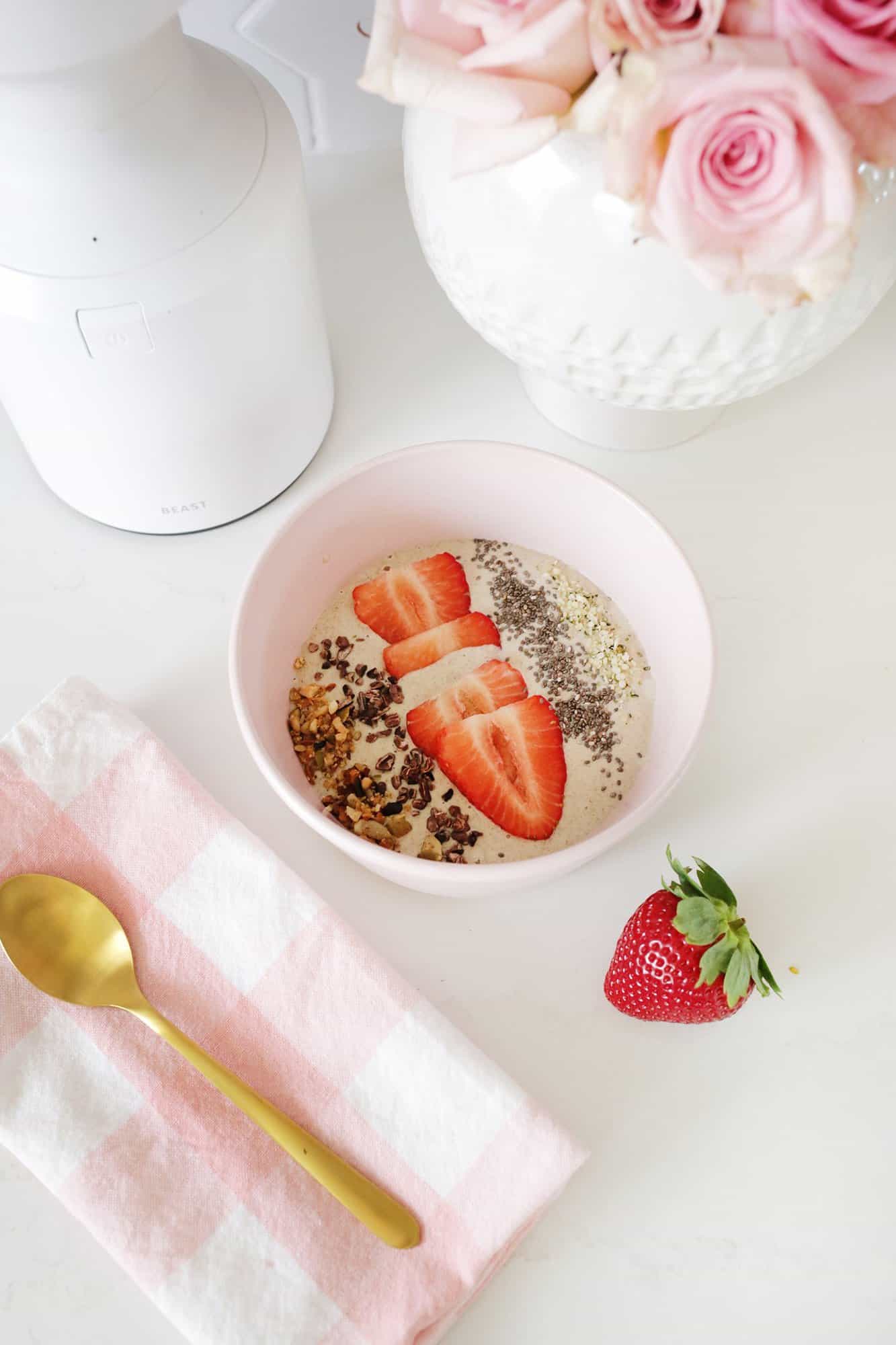 Strawberry smoothie bowl in front of the blender