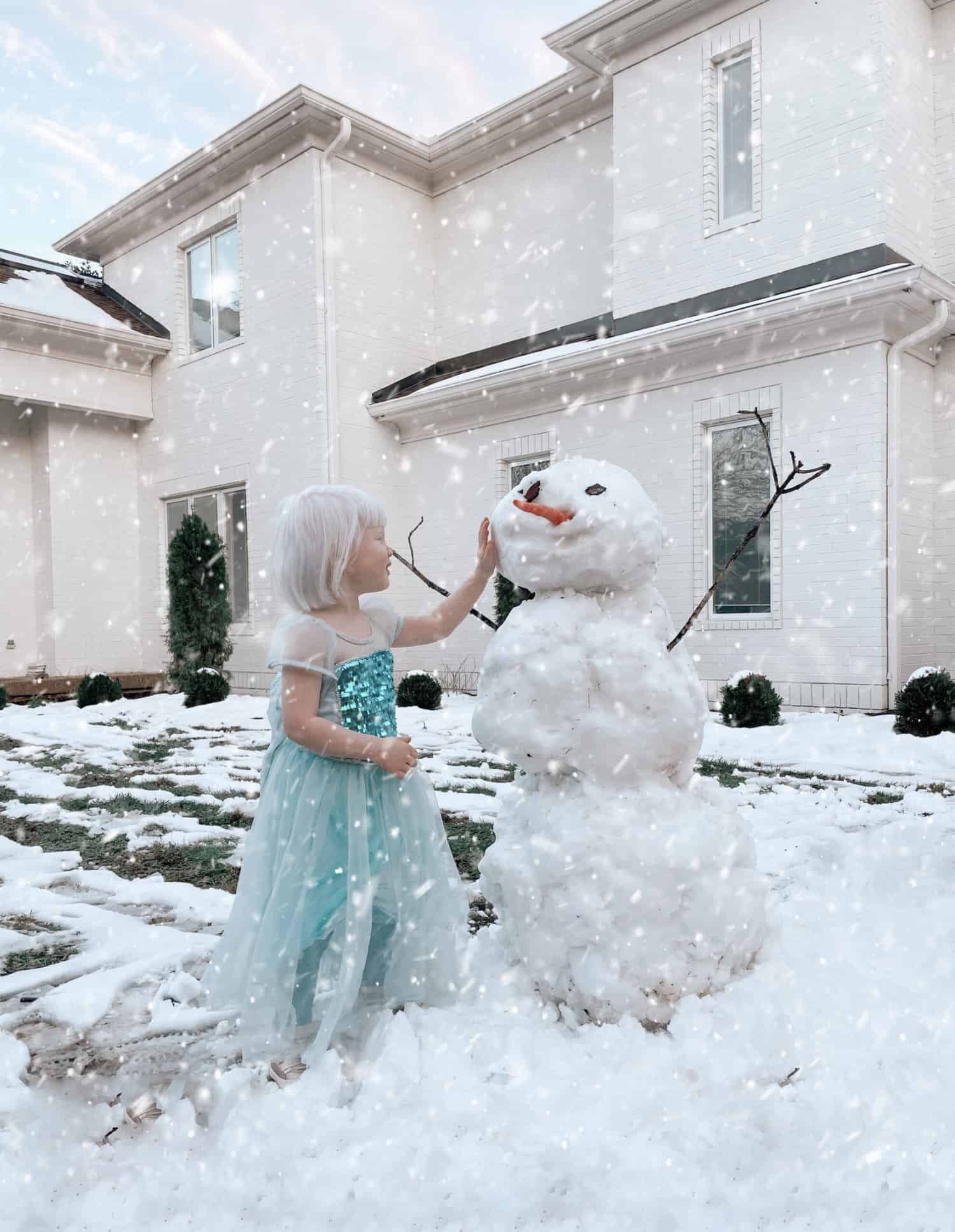 Girl in blue dress next to a snowman 
