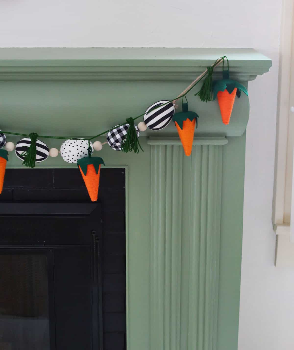 Carrot yarn garland hanging on green fireplace