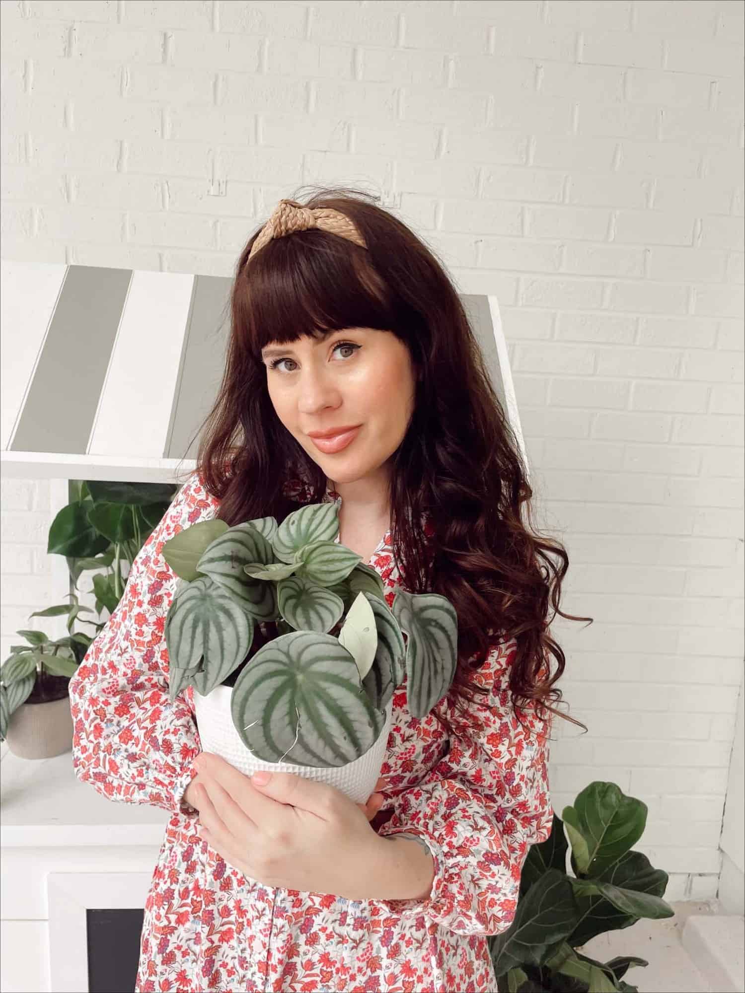 Woman wearing floral dress holding a potted plant