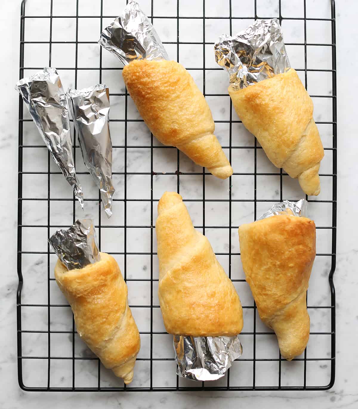 carrot-shaped pastries with foil on wire rack